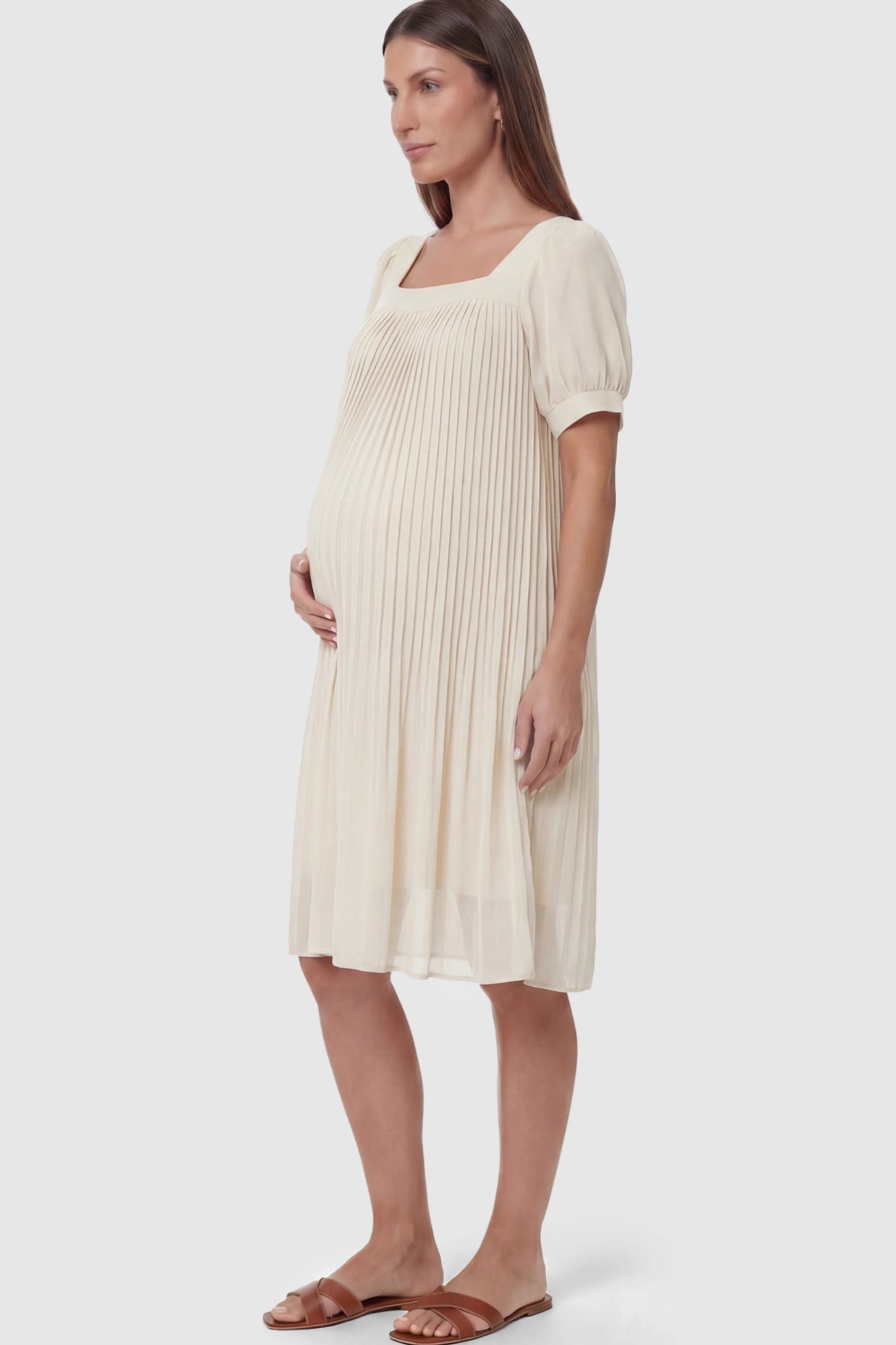 Pleated Front Square Neck Maternity Dress Pleated Front Square Neck Maternity Dress in Off White featuring accordion pleats and short sleeves on a pregnant model.