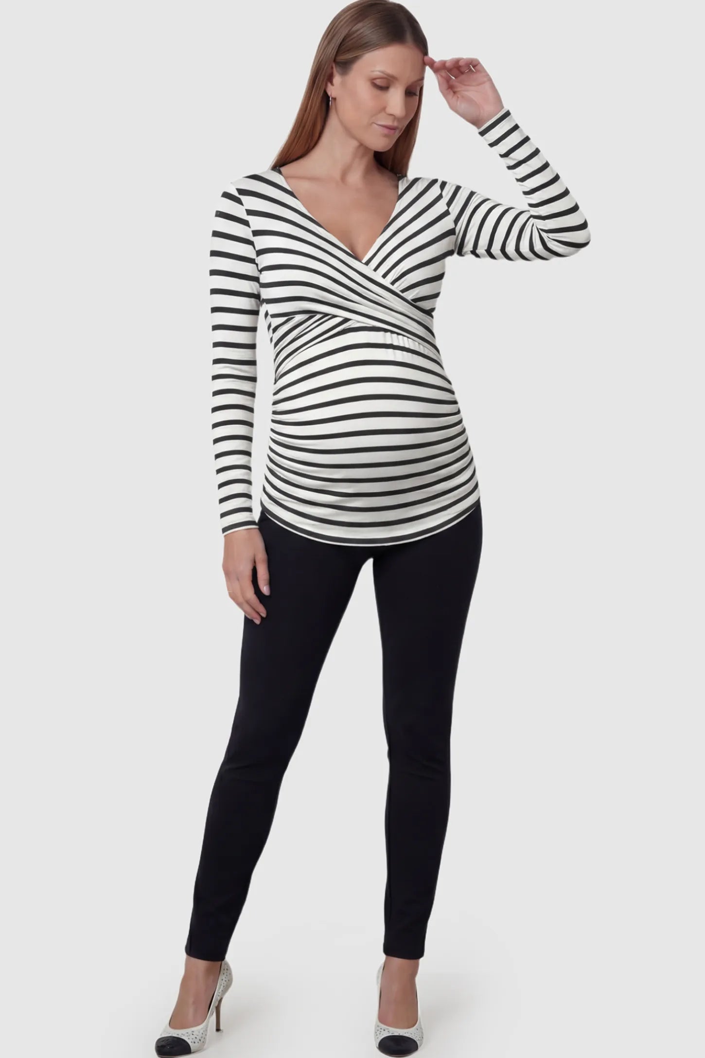 Striped Wrap Front Maternity & Nursing Top Striped Wrap Front Nursing Top in White with crossover neckline on a pregnant model.
