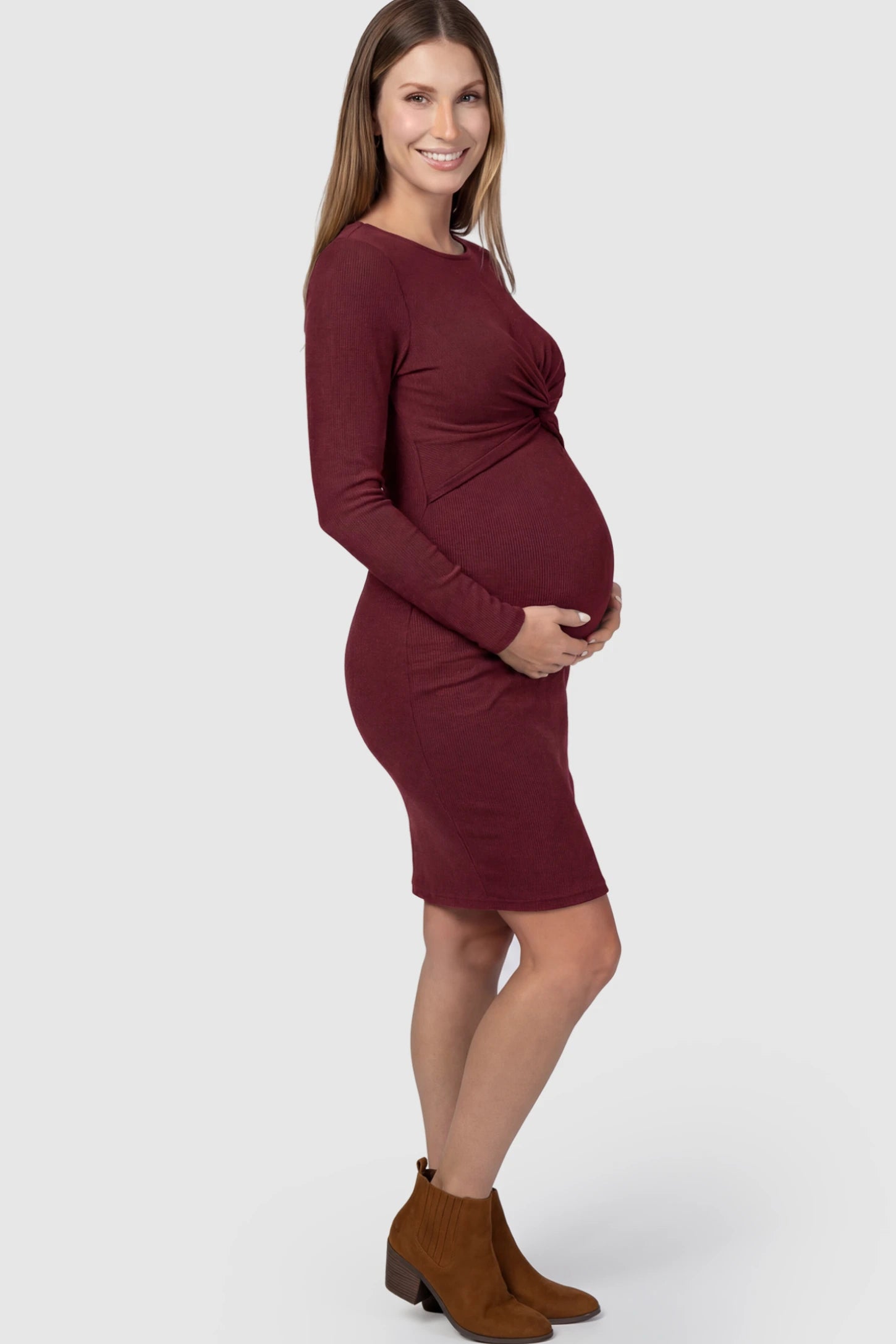 Ribbed Twist Front Long Sleeve Bodycon Maternity Short Dress Twist-Front Long Sleeve Ribbed Maternity Mini Dress in Red featuring a textured knit finish on a pregnant model.