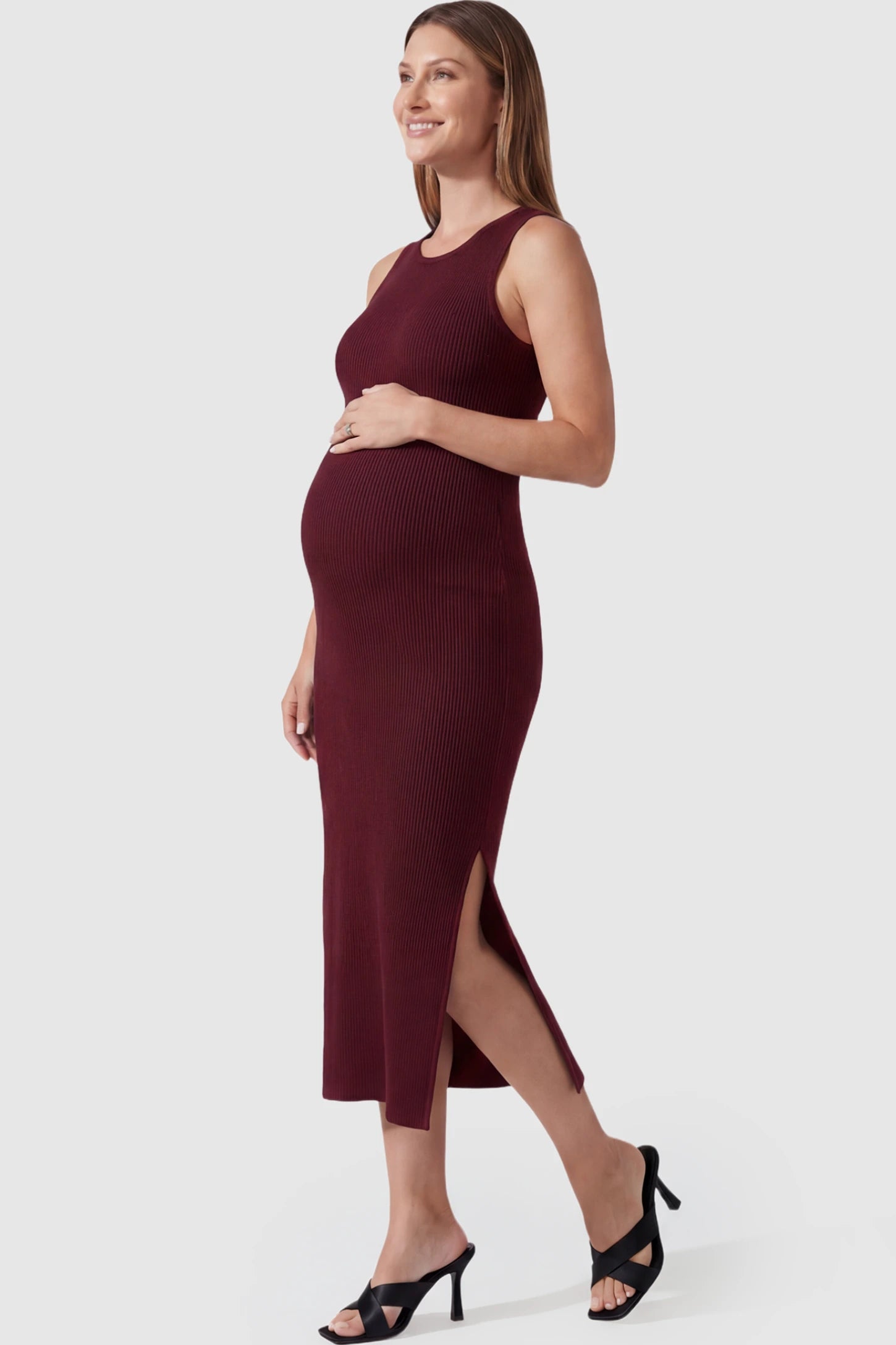 Ribbed Knit Sleeveless Maternity Midi Dress in Burgundy featuring a side slit and crew neck on a pregnant model.