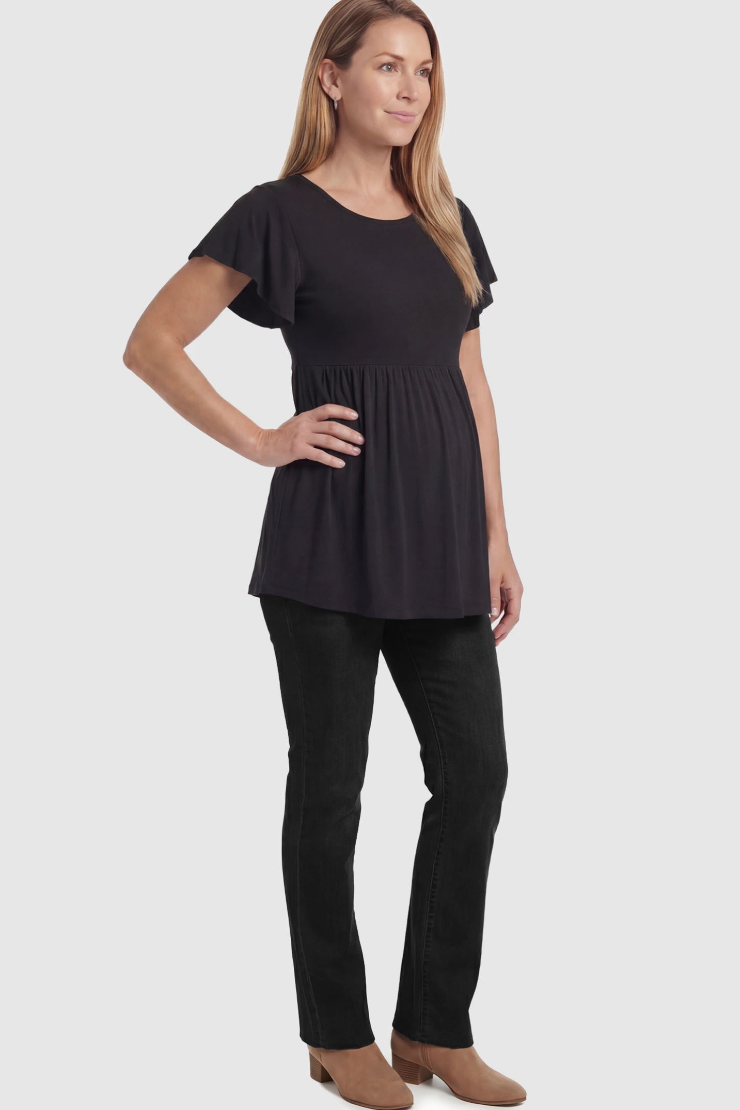 Solid Ruffled-Sleeve Flowy Maternity Top Solid Ruffled-Sleeve Flowy Maternity Top in Black featuring a pleated empire waist paired with black jeans and boots on a pregnant model in  a full body image.