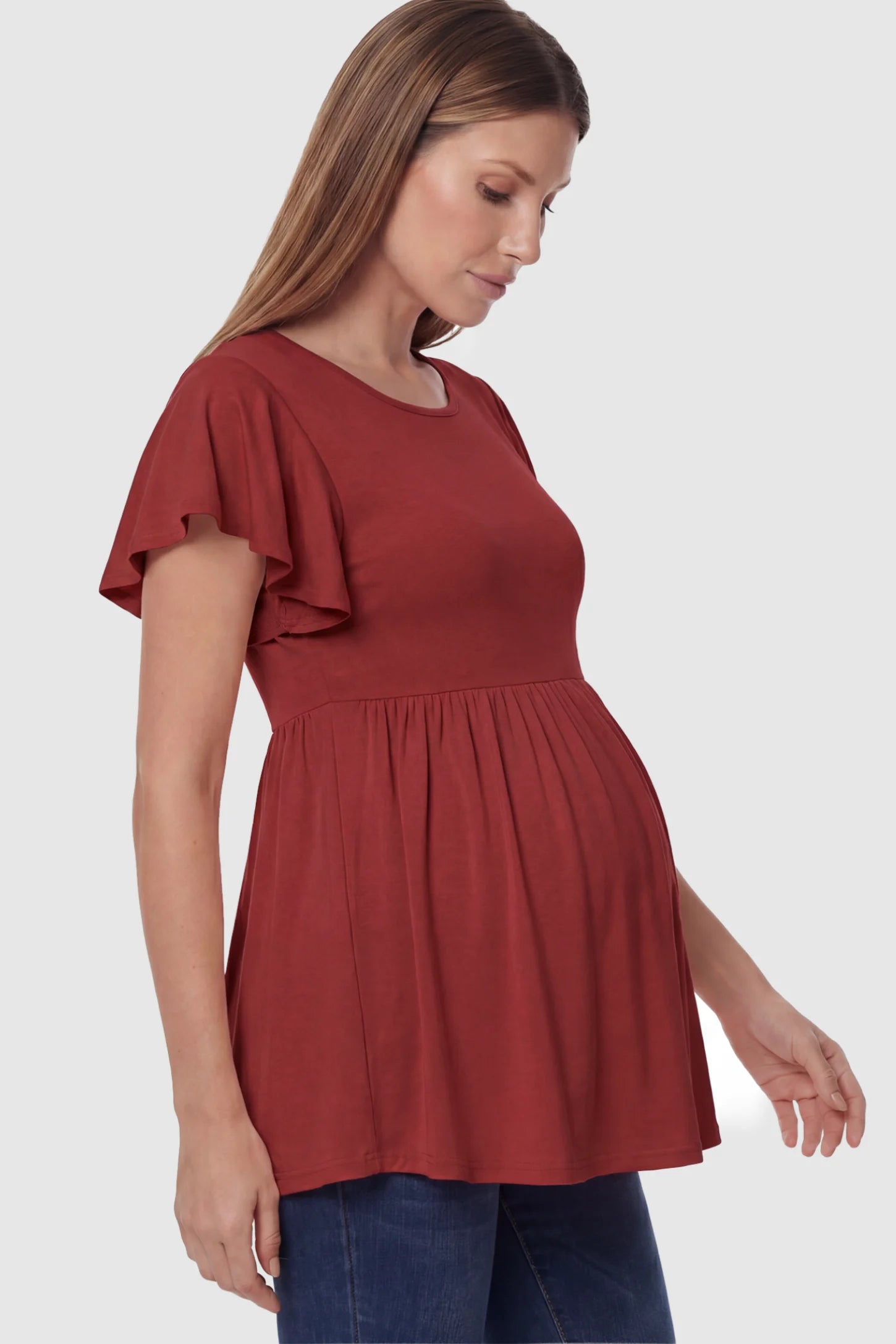 Solid Ruffled-Sleeve Flowy Maternity Top in Red featuring a pleated empire waist on a pregnant model in side view.