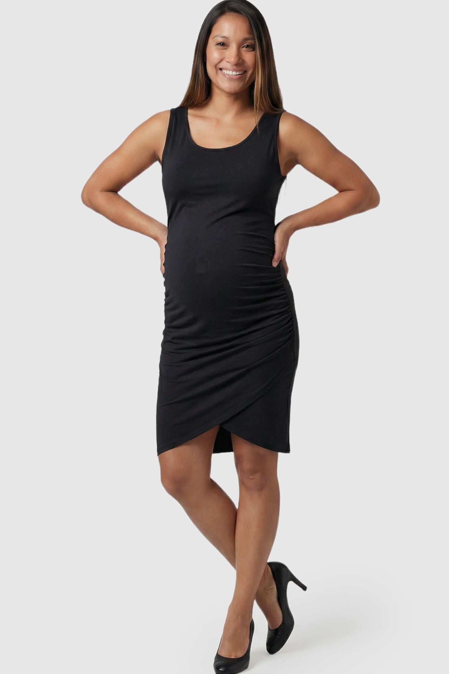 Ruched Tulip-Hem Sleeveless Bodycon Maternity Dress Ruched Tulip-Hem Bodycon Maternity Dress in Black featuring a side-ruched pencil skirt on a pregnant model.