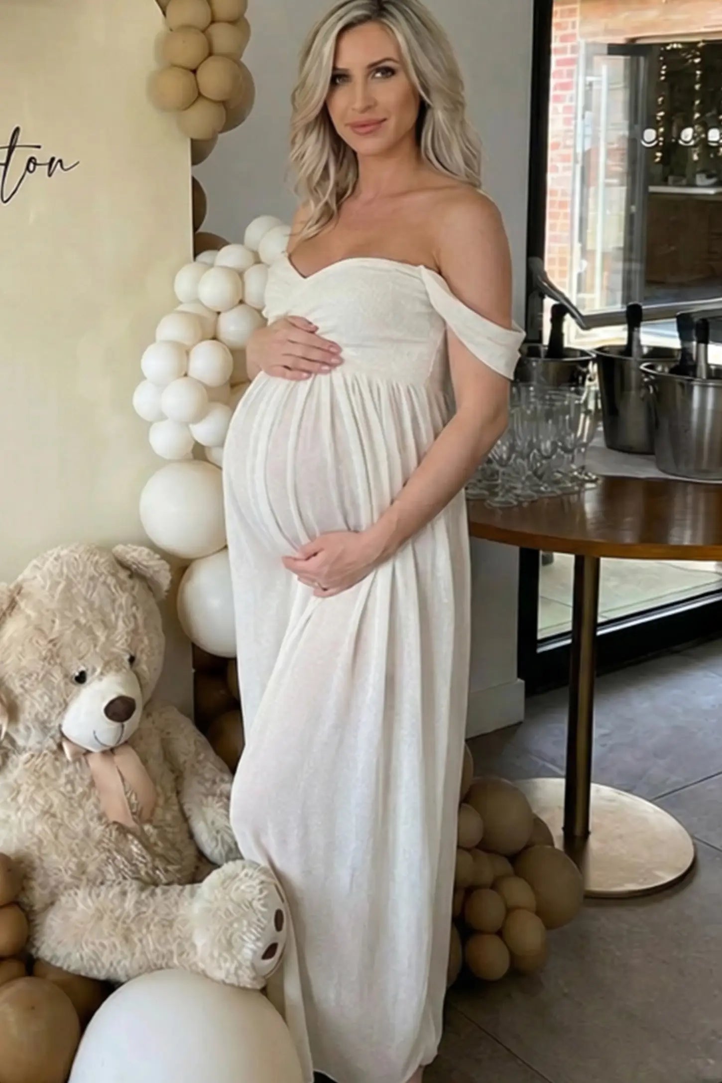 Lace Off Shoulder Slit Front Maternity Photoshoot Gown Lace Off Shoulder Slit Front Maternity Photoshoot Gown in white featuring a flowy chiffon opening on a pregnant model.
