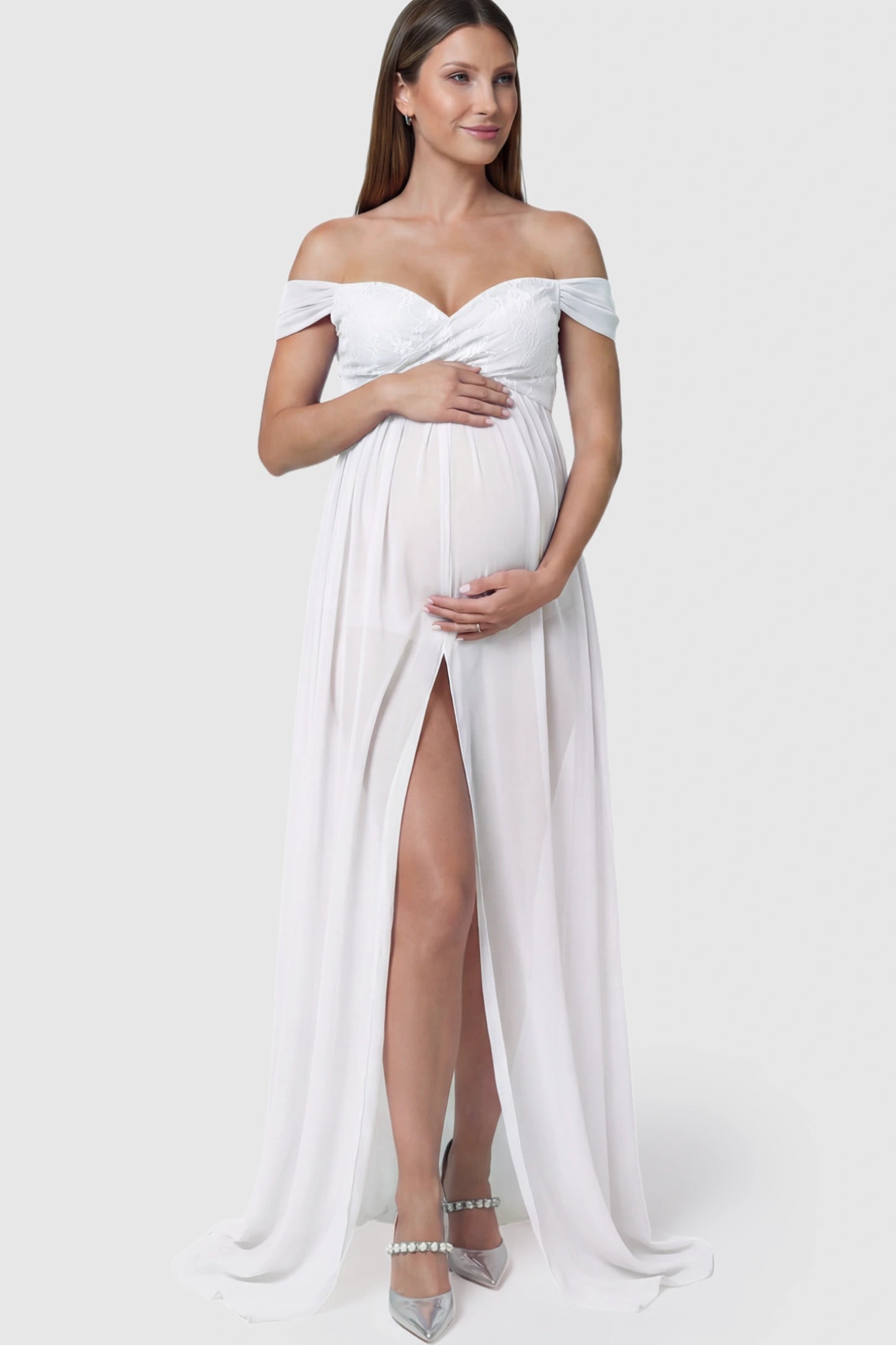Lace Off Shoulder Slit Front Maternity Photoshoot Gown Lace Off Shoulder Slit Front Maternity Photoshoot Gown in white featuring a flowy chiffon opening on a pregnant model.
