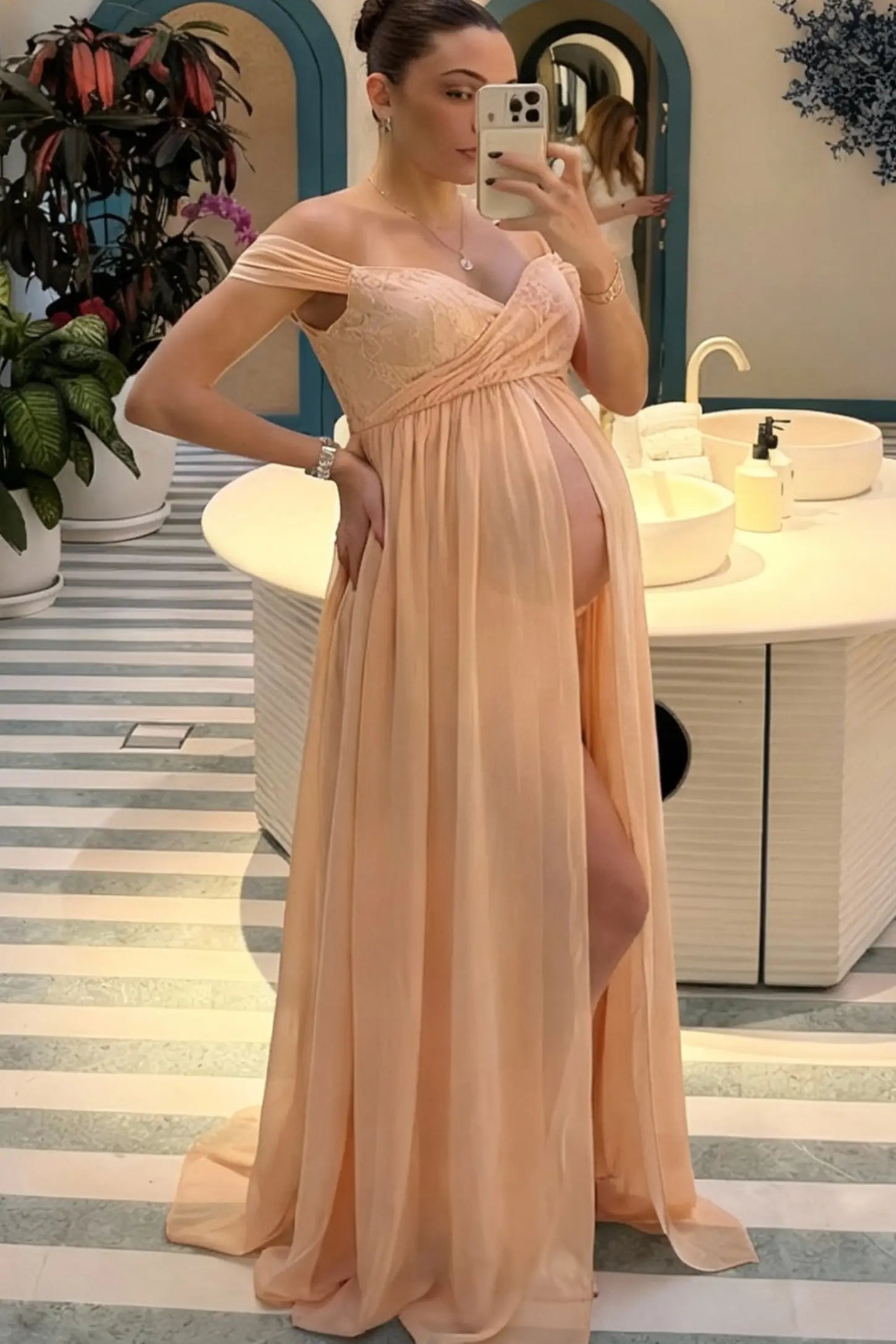 Lace Off Shoulder Slit Front Maternity Photoshoot Gown Lace Off Shoulder Slit Front Maternity Photoshoot Gown in light peach featuring a flowy chiffon opening on a pregnant model.
