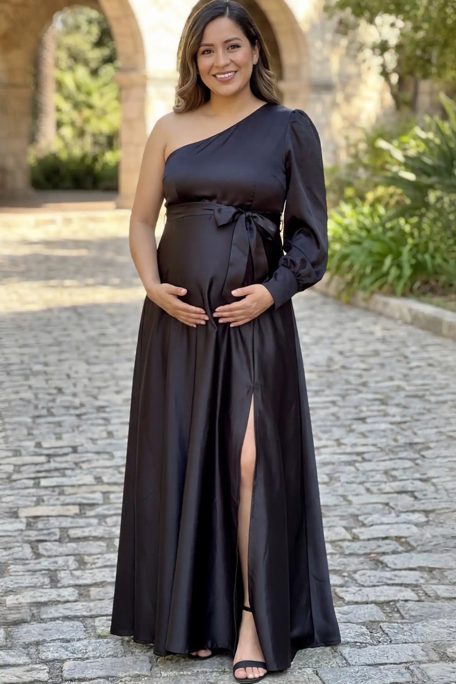Satin One Shoulder Belted Maternity Maxi Dress Satin One-Shoulder Belted Maternity Maxi Dress in Black featuring a side slit and waist tie on a pregnant model.