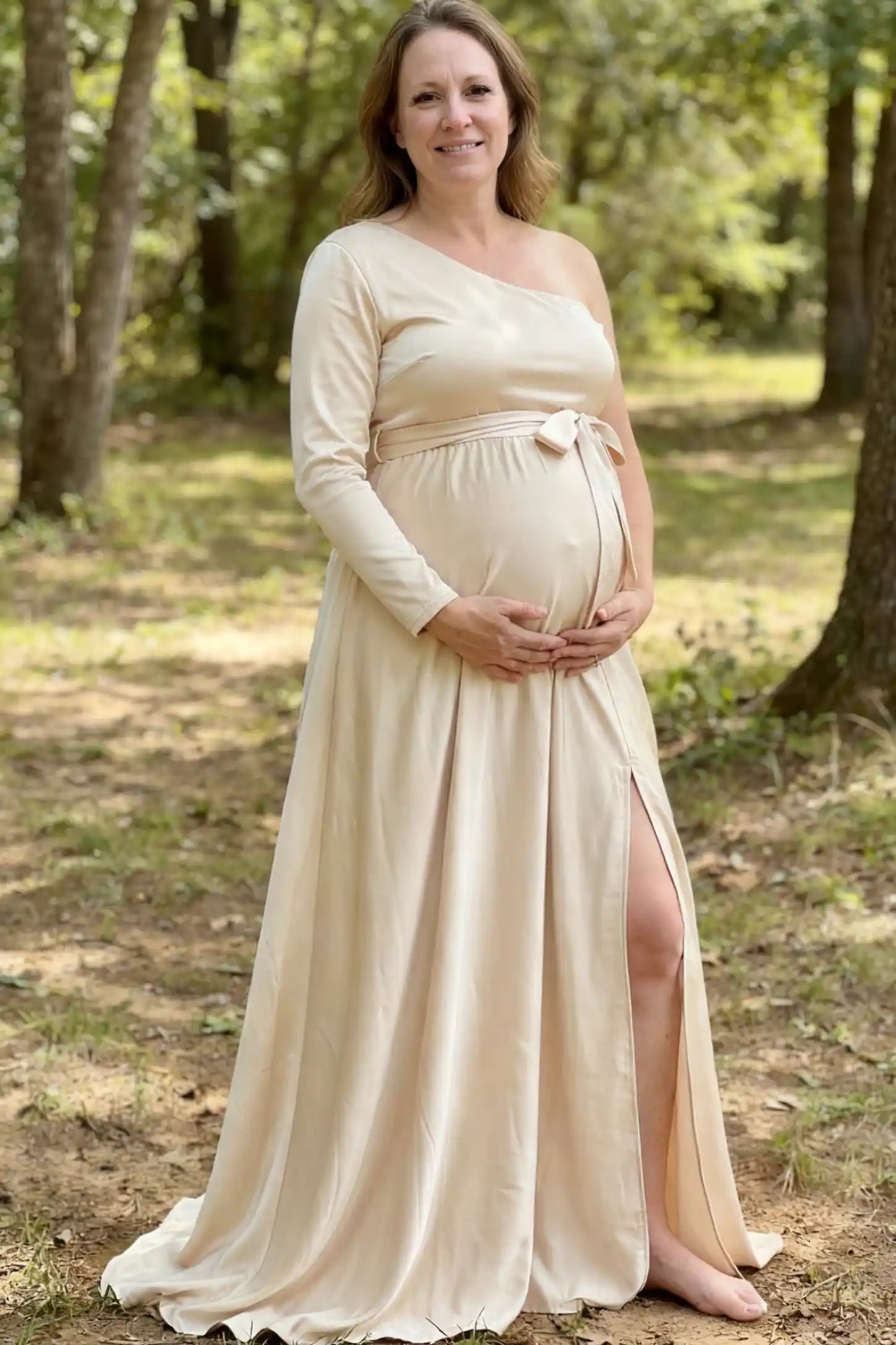 Satin One Shoulder Belted Maternity Maxi Dress Satin One-Shoulder Belted Maternity Maxi Dress in Light gray featuring a side slit and waist tie on a pregnant model.