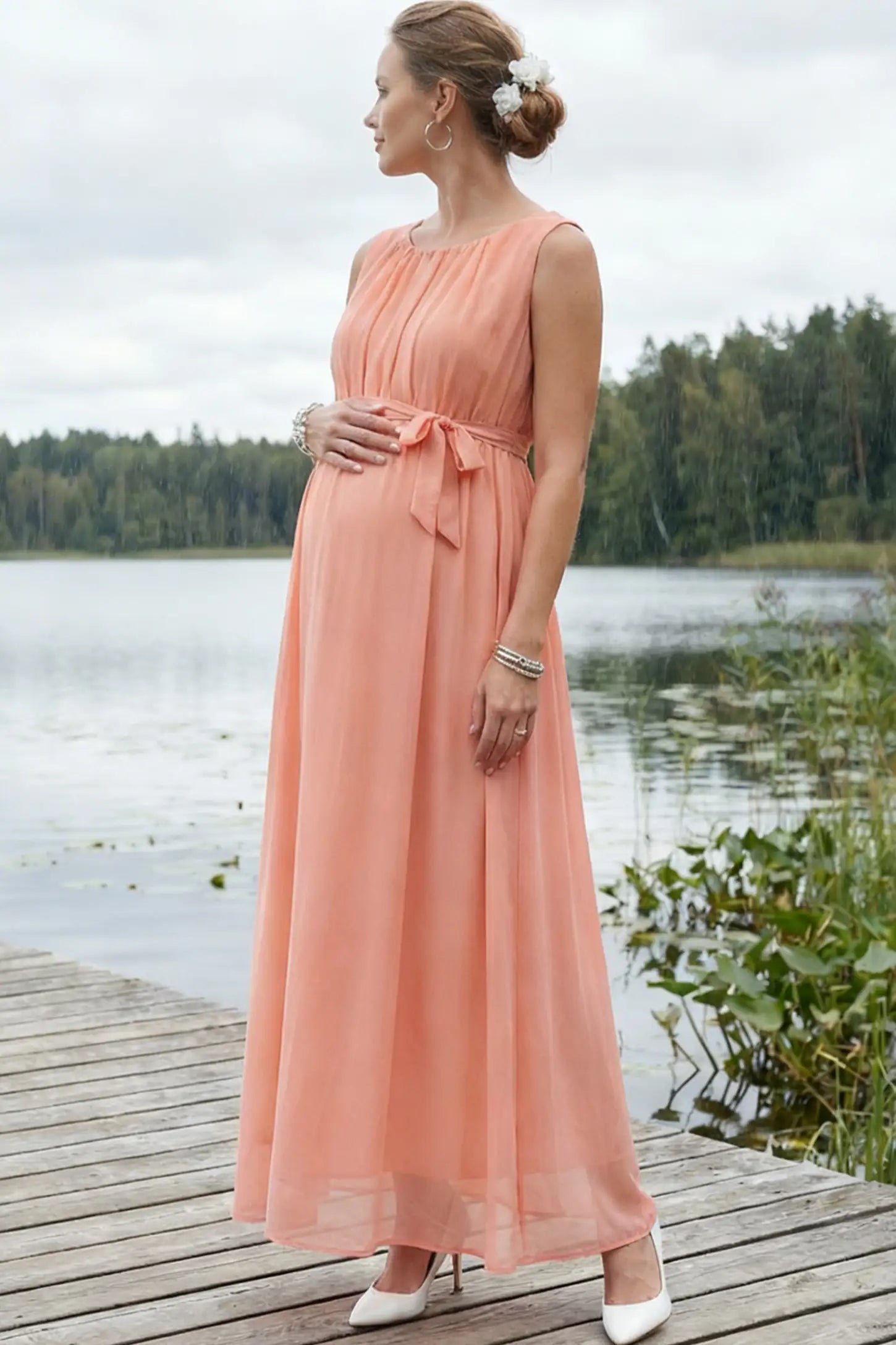 Empire Waist Tie-Front Sleeveless Maternity Maxi Dress Empire Waist Tie-Front Sleeveless Maternity Maxi Dress in Pink featuring a tie front and empire waist on a pregnant model.