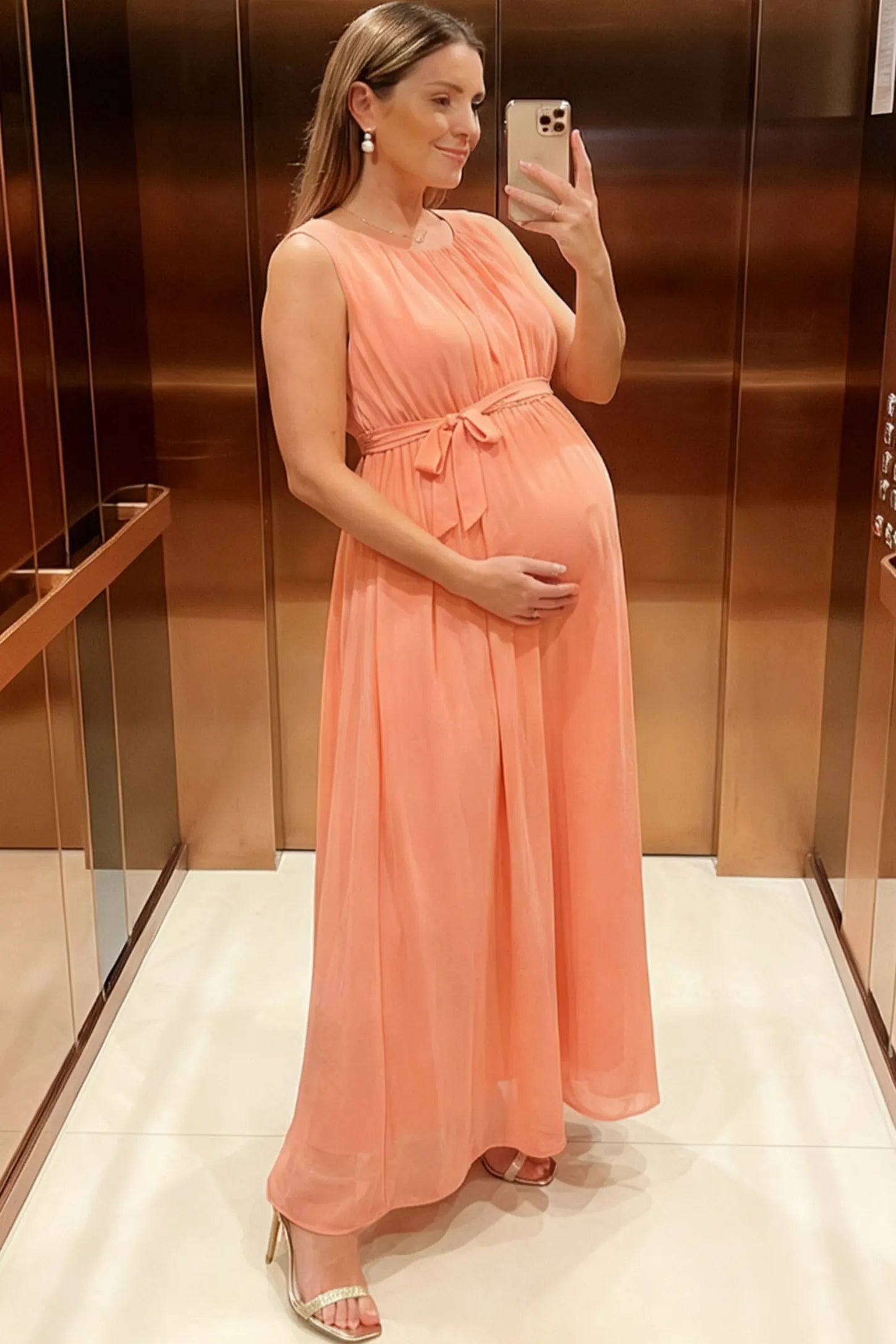 Empire Waist Tie-Front Sleeveless Maternity Maxi Dress Empire Waist Tie-Front Sleeveless Maternity Maxi Dress in Pink featuring a tie front and empire waist on a pregnant model.