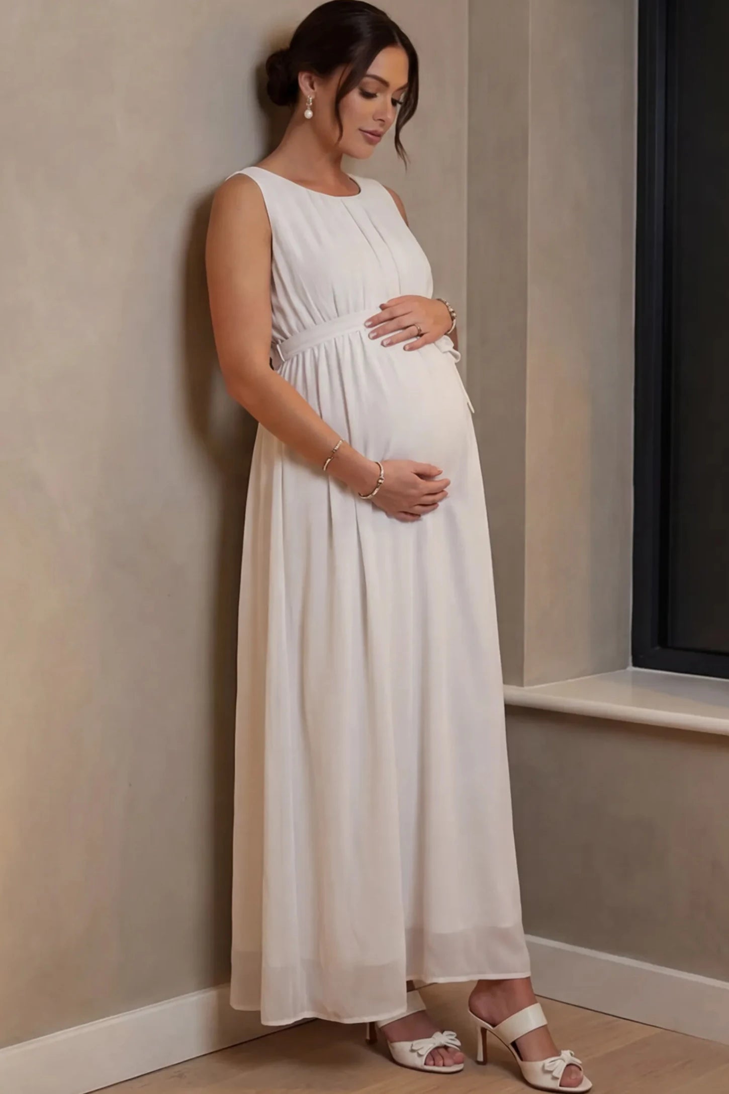 Empire Waist Tie-Front Sleeveless Maternity Maxi Dress Empire Waist Tie-Front Sleeveless Maternity Maxi Dress in White featuring a tie front and empire waist on a pregnant model.