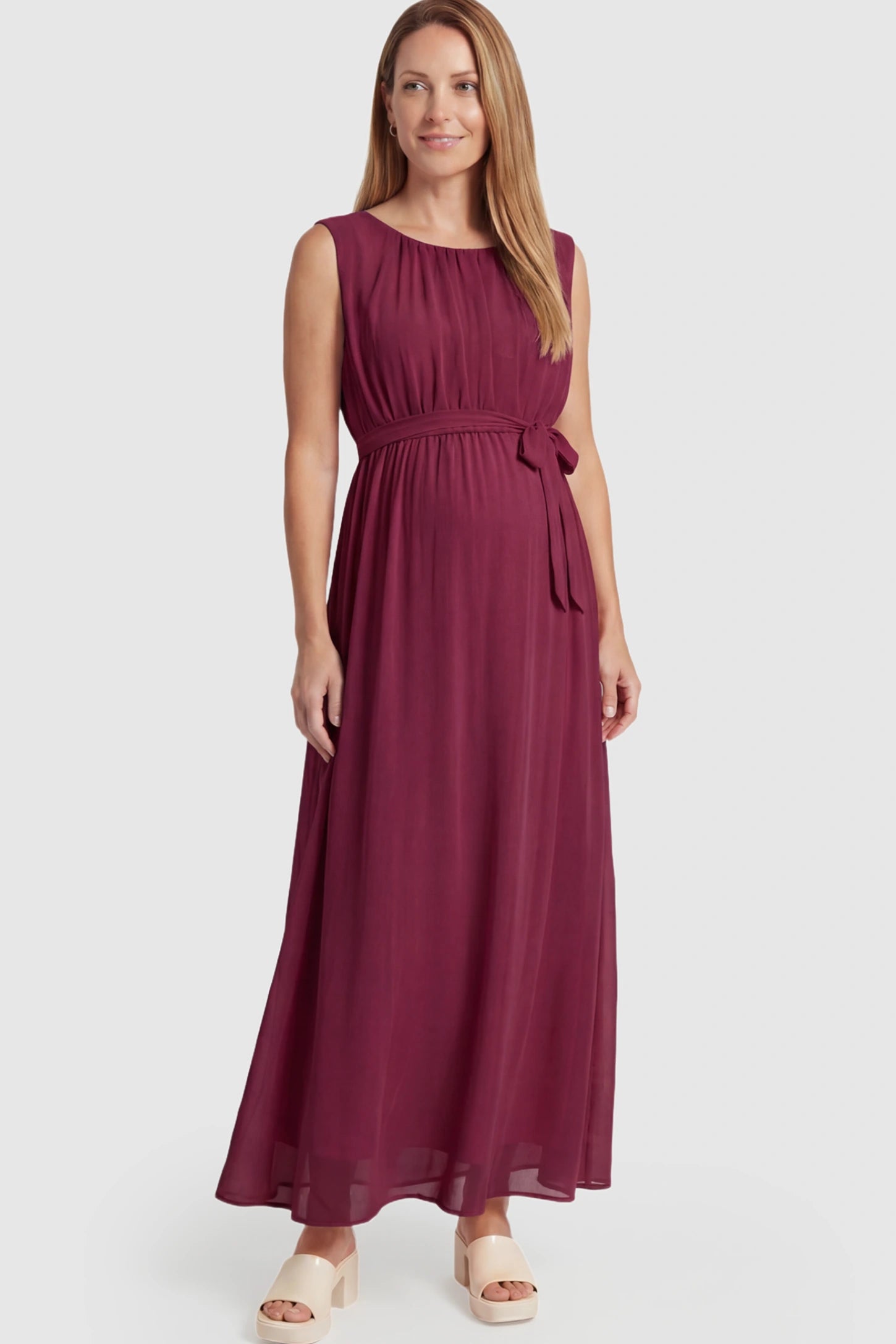 Empire Waist Tie-Front Sleeveless Maternity Maxi Dress Empire Waist Tie-Front Sleeveless Maternity Maxi Dress in Wine Red featuring a tie front and empire waist on a postpartum model.