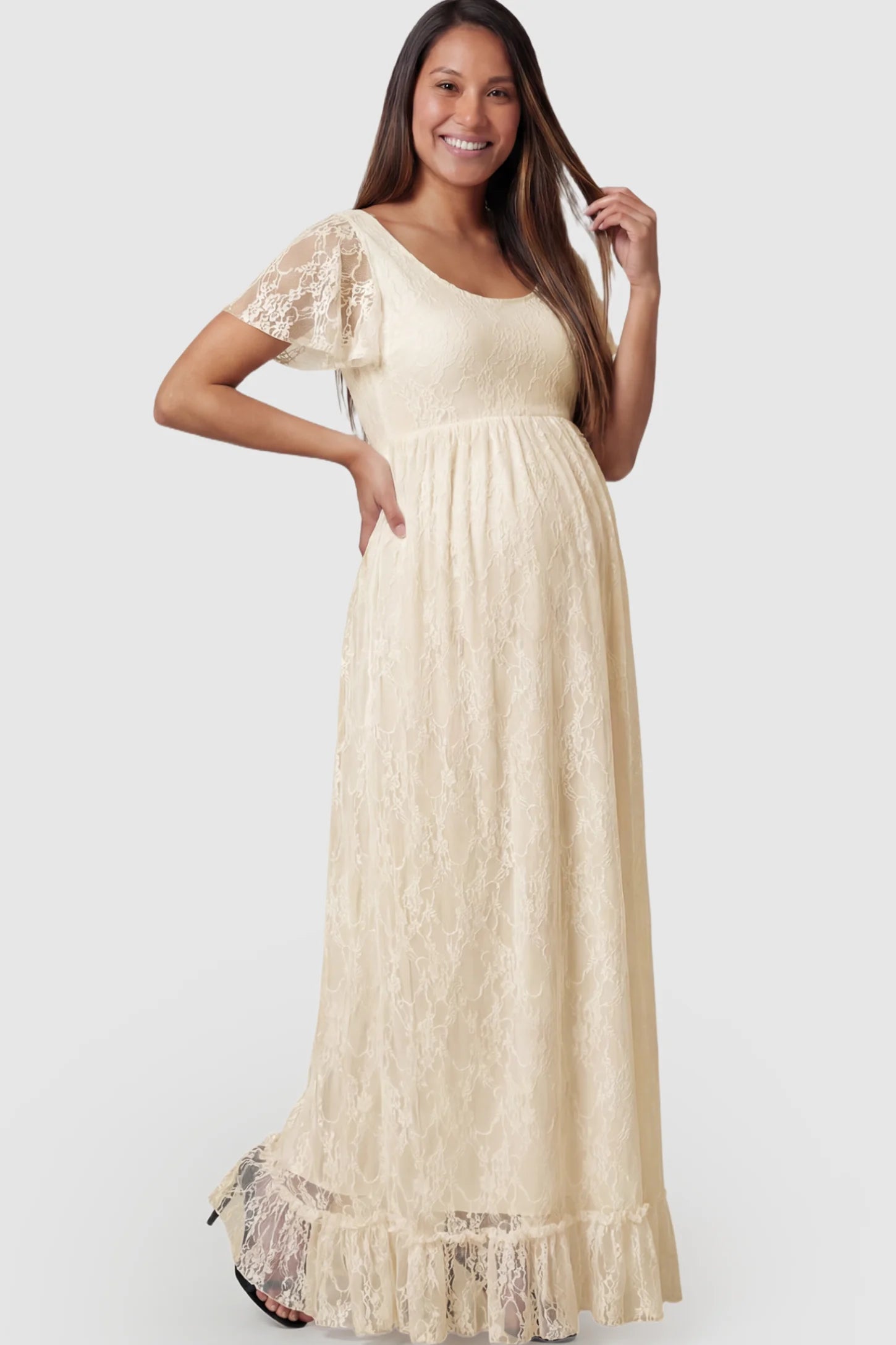 Floral Lace Flutter Sleeve Maternity Maxi Dress Floral Lace Flutter Sleeve Maxi Maternity Dress in Beige featuring delicate lace and an empire waist on a pregnant model.