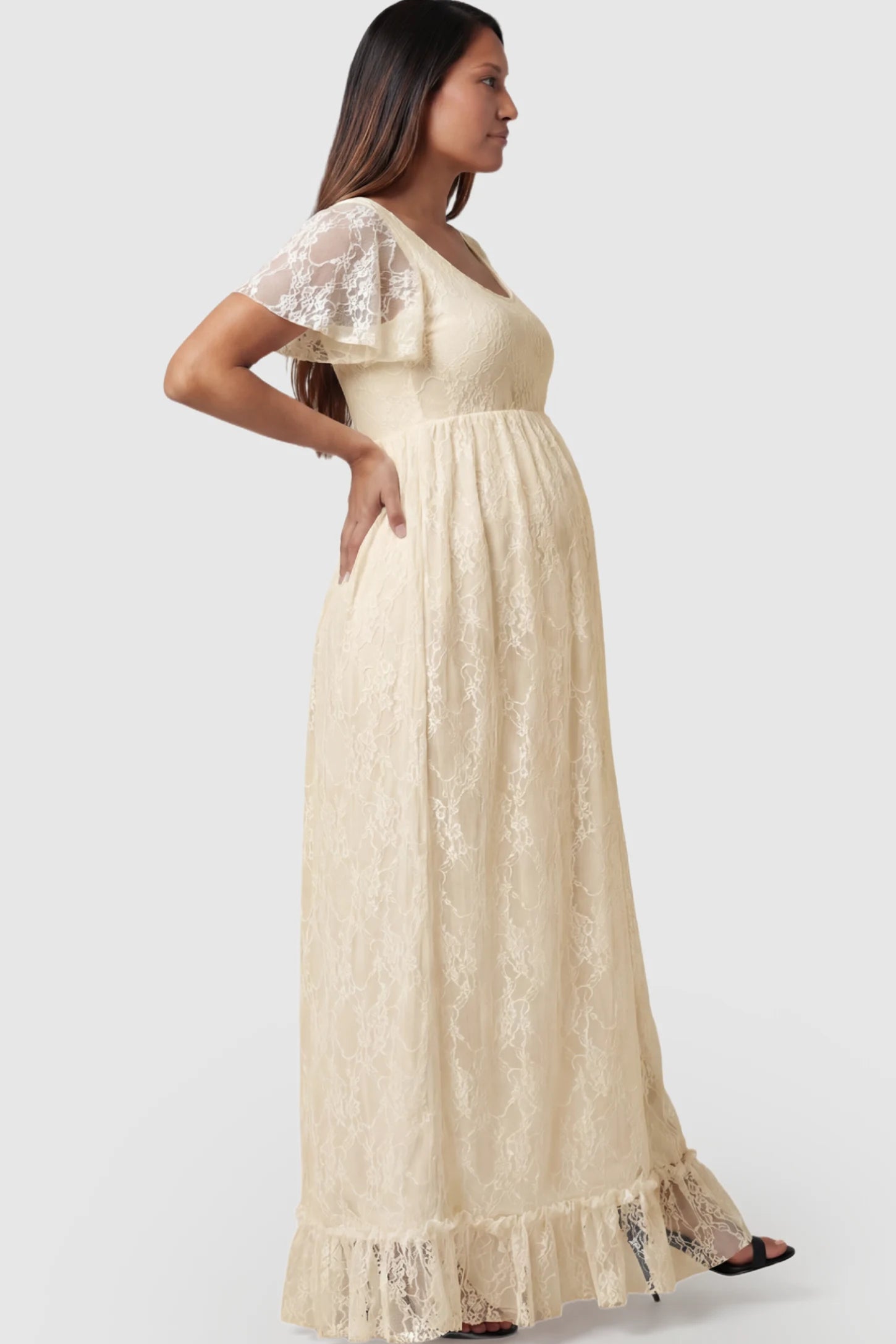 Floral Lace Flutter Sleeve Maternity Maxi Dress Floral Lace Flutter Sleeve Maxi Maternity Dress in Beige featuring delicate lace and an empire waist on a pregnant model.