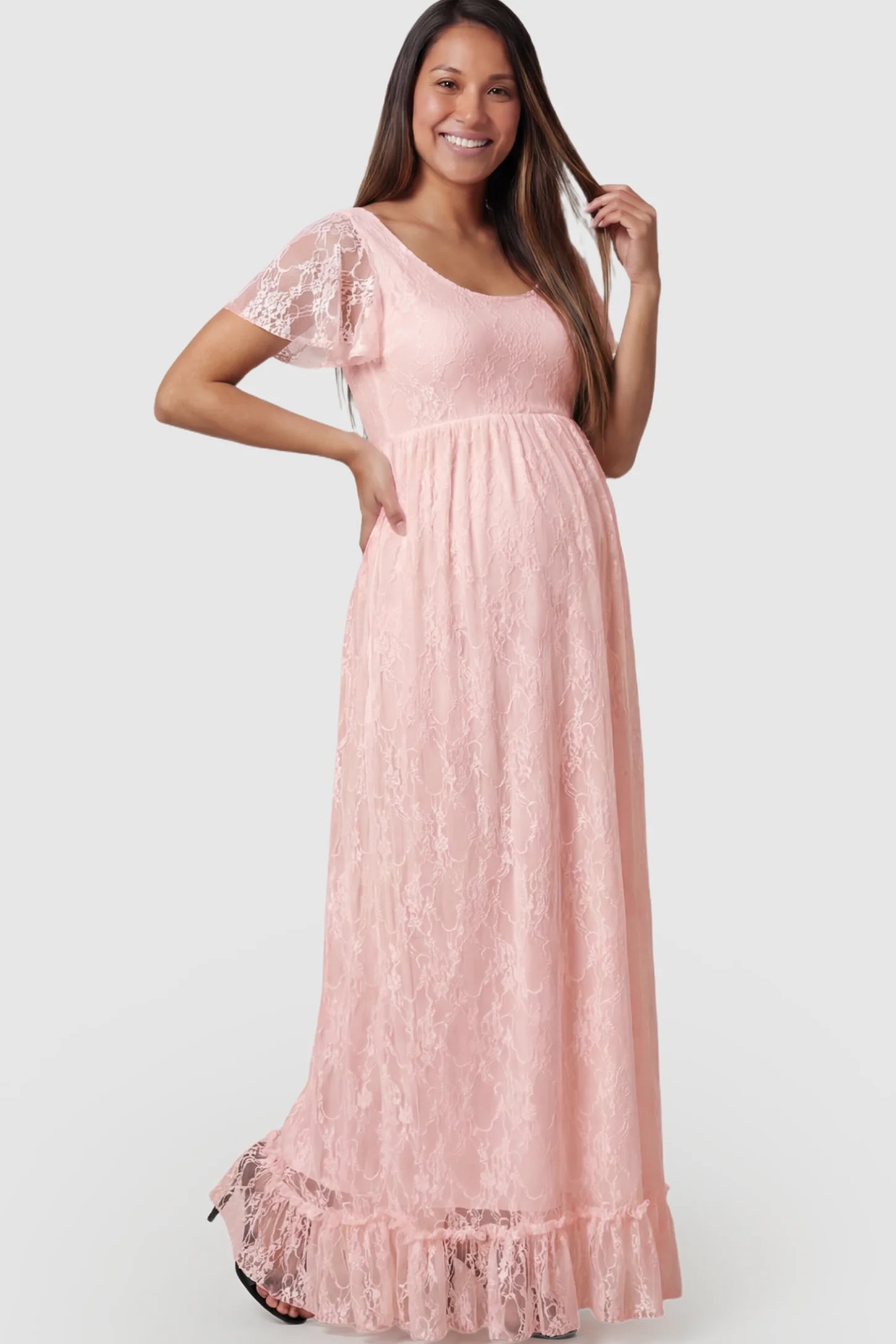 Floral Lace Flutter Sleeve Maternity Maxi Dress Floral Lace Flutter Sleeve Maxi Maternity Dress in Pink featuring delicate lace and an empire waist on a pregnant model.