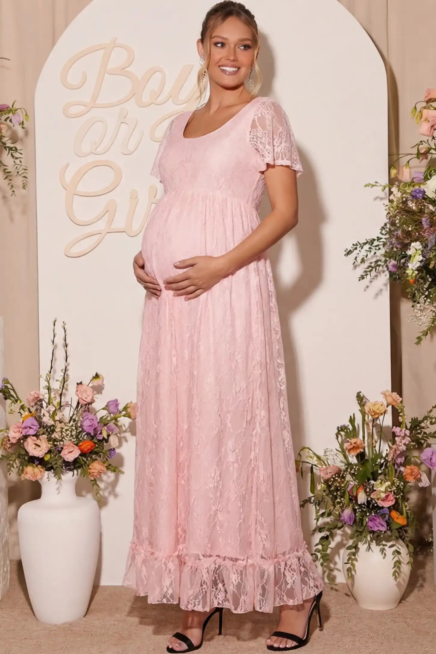 Floral Lace Flutter Sleeve Maternity Maxi Dress Floral Lace Flutter Sleeve Maxi Maternity Dress in Pink featuring delicate lace and an empire waist on a pregnant model.