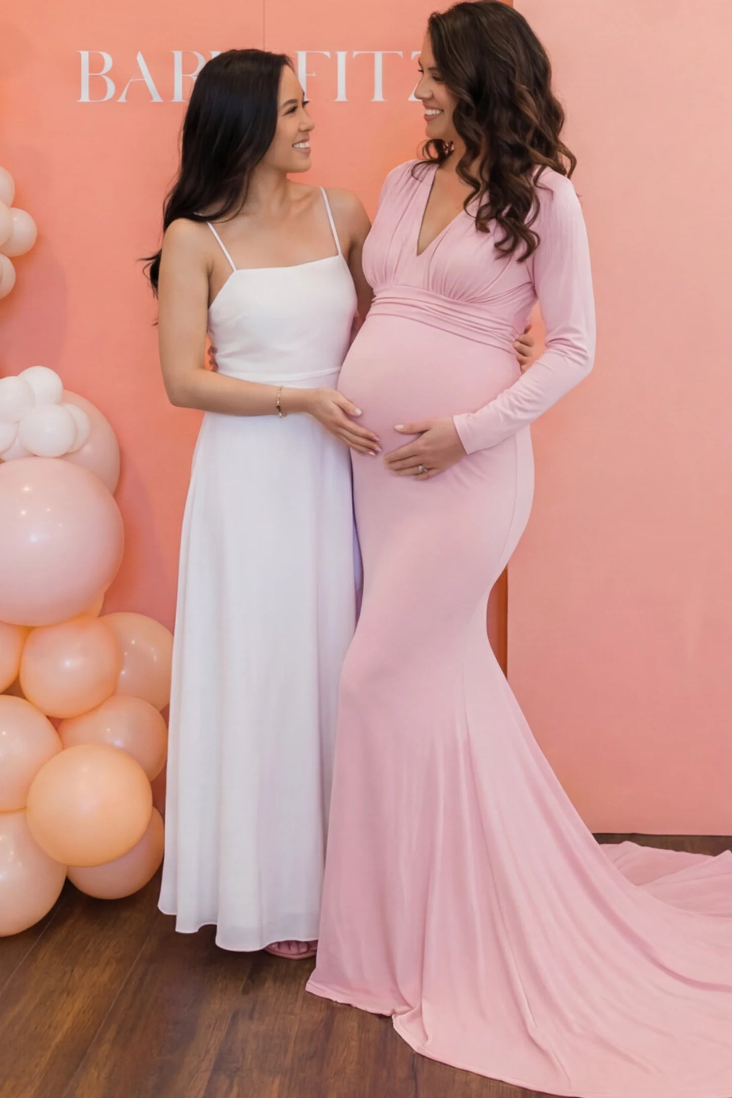 Pure Cotton V-Neck Long Sleeve Maternity Photoshoot Gown Pure Cotton V-Neck Long Sleeve Maternity Photoshoot Gown in Pink featuring a floor-pooling train on a pregnant model posing with a friend.