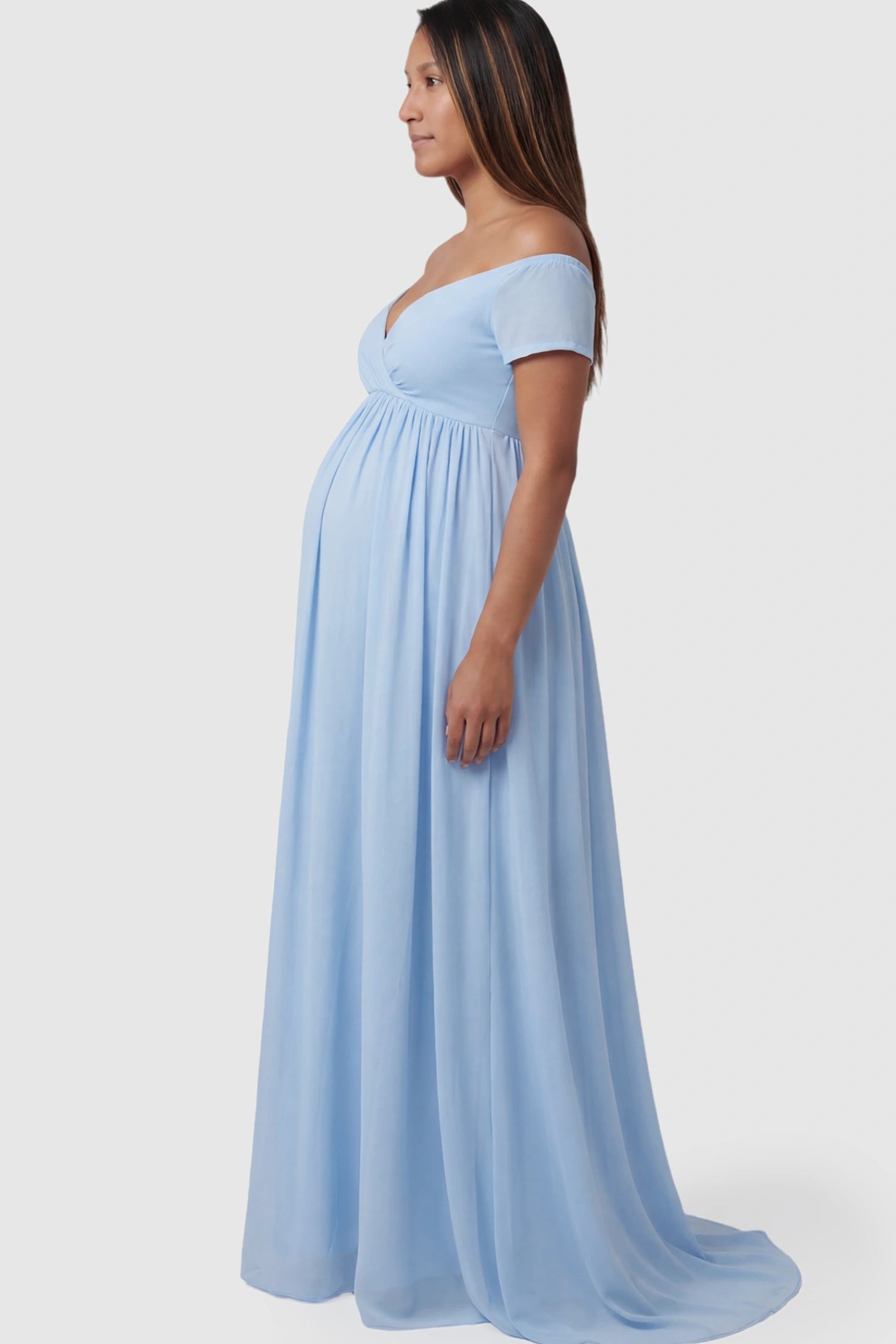 Solid Off Shoulder Flowy Maternity Maxi Dress Solid Off-the-Shoulder Sweetheart Maternity Maxi Dress in Light Blue featuring an empire waist on a pregnant model.