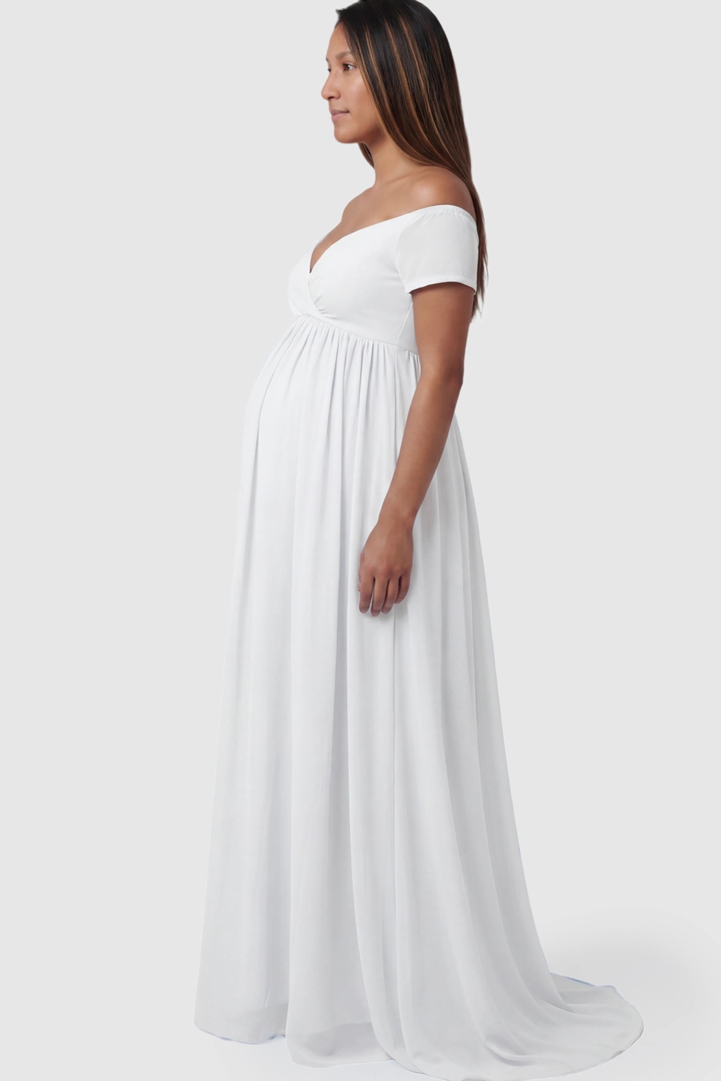 Solid Off Shoulder Flowy Maternity Maxi Dress Solid Off-the-Shoulder Sweetheart Maternity Maxi Dress in White featuring an empire waist on a pregnant model.