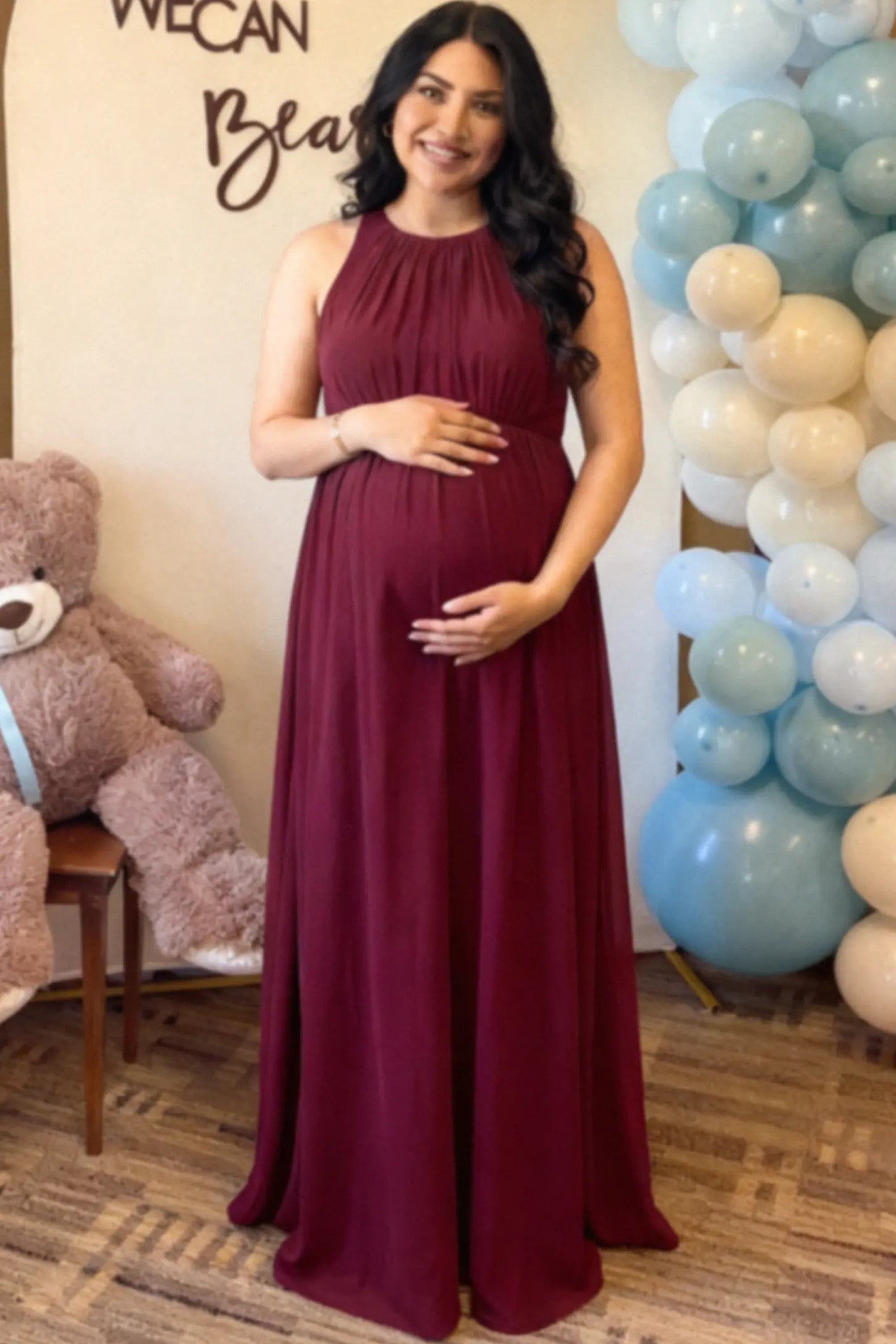 Pleated Mesh Sleeveless Maternity Photoshoot Dress Pleated Mesh Sleeveless Maternity Maxi Dress in burgundy with an empire waist on a pregnant model.