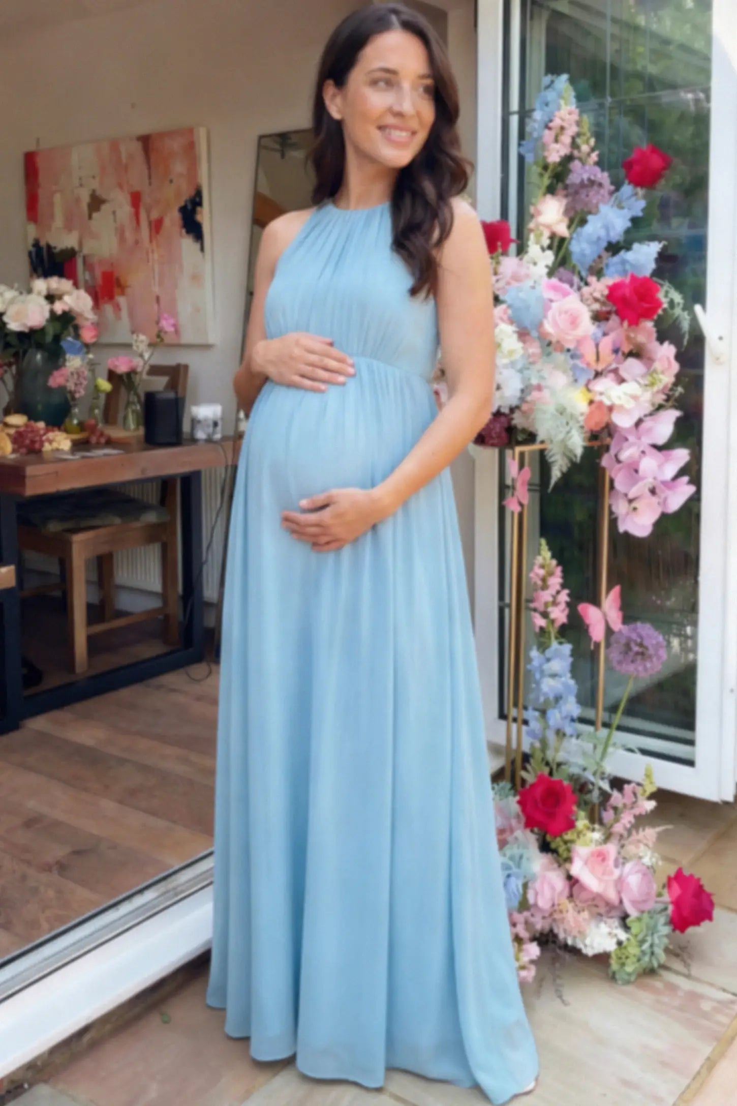 Pleated Mesh Sleeveless Maternity Photoshoot Dress Pleated Mesh Sleeveless Maternity Maxi Dress in light blue with an empire waist on a pregnant model.