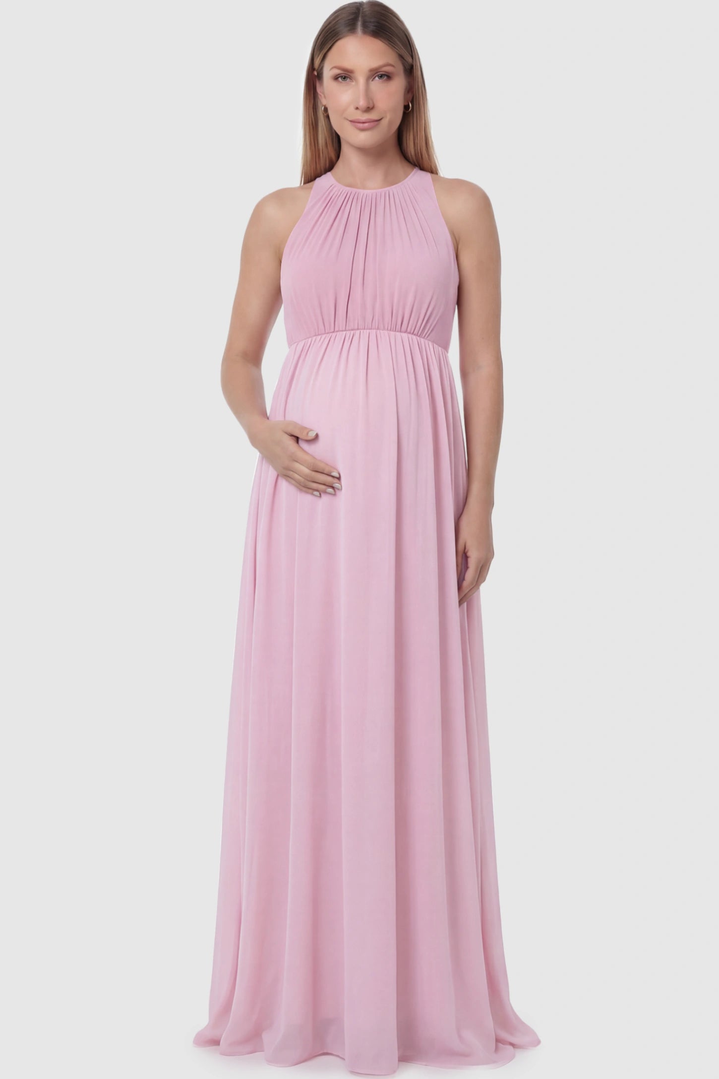 Pleated Mesh Sleeveless Maternity Photoshoot Dress Pleated Mesh Sleeveless Maternity Maxi Dress in pink with an empire waist on a pregnant model.