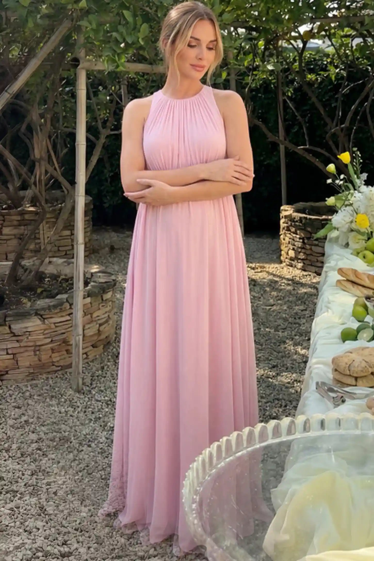 Pleated Mesh Sleeveless Maternity Photoshoot Dress Pleated Mesh Sleeveless Maternity Maxi Dress in pink with an empire waist on a pregnant model.