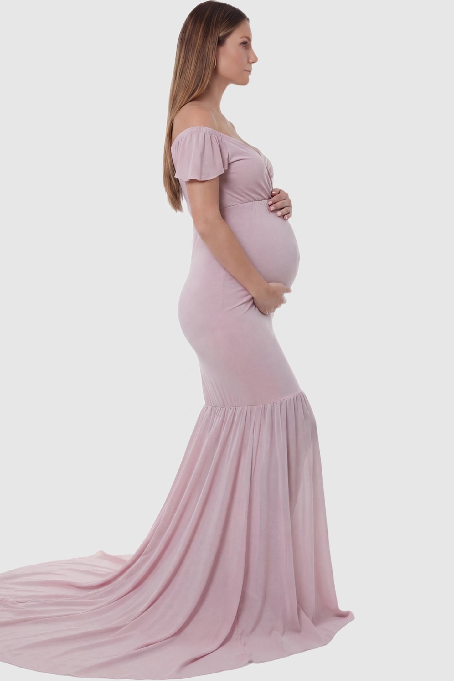 Solid Off Shoulder Fitted Maternity Photoshoot Gown Solid Off Shoulder Fitted Maternity Photoshoot Gown in pink featuring a sweetheart cross-front bodice and flowing chiffon train on a pregnant model.