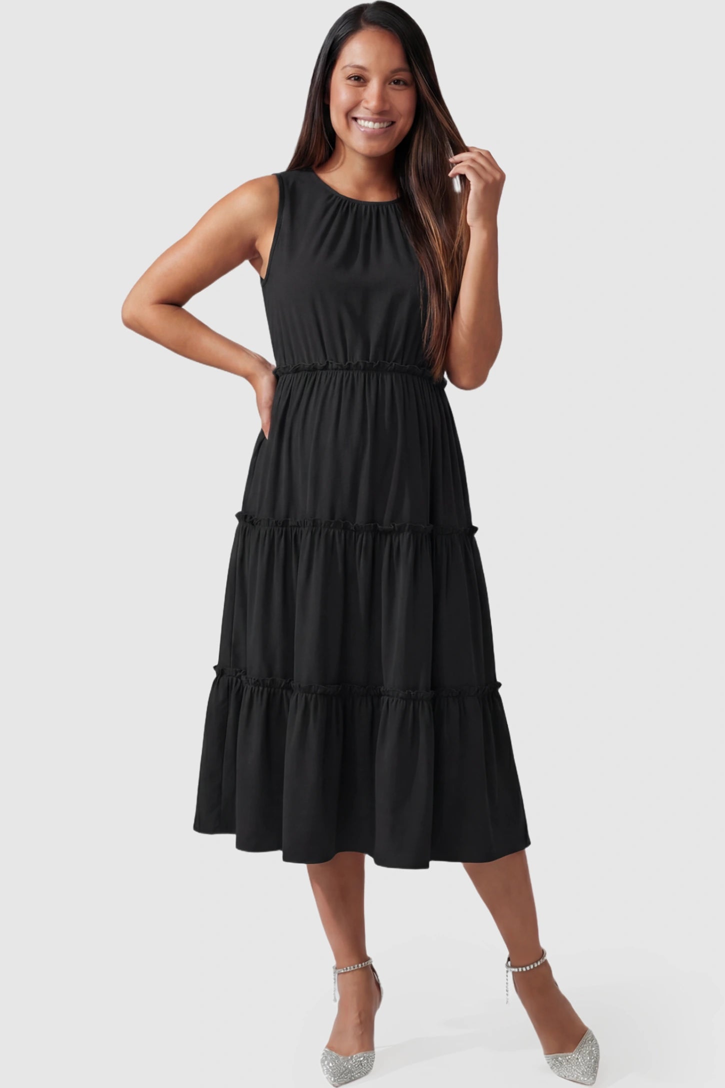 Solid Sleeveless Ruffle Tiered Maternity Midi Dress Solid Sleeveless Ruffle Tiered Maternity Midi Dress in black featuring a ruffle tiered skirt on a pregnant model.
