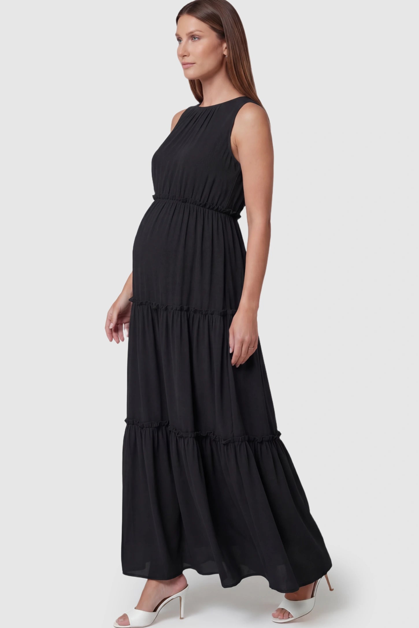 Solid Sleeveless Ruffle Tiered Maternity Midi Dress Solid Sleeveless Ruffle Tiered Maternity Midi Dress in Black featuring a ruffle tiered skirt on a pregnant model.