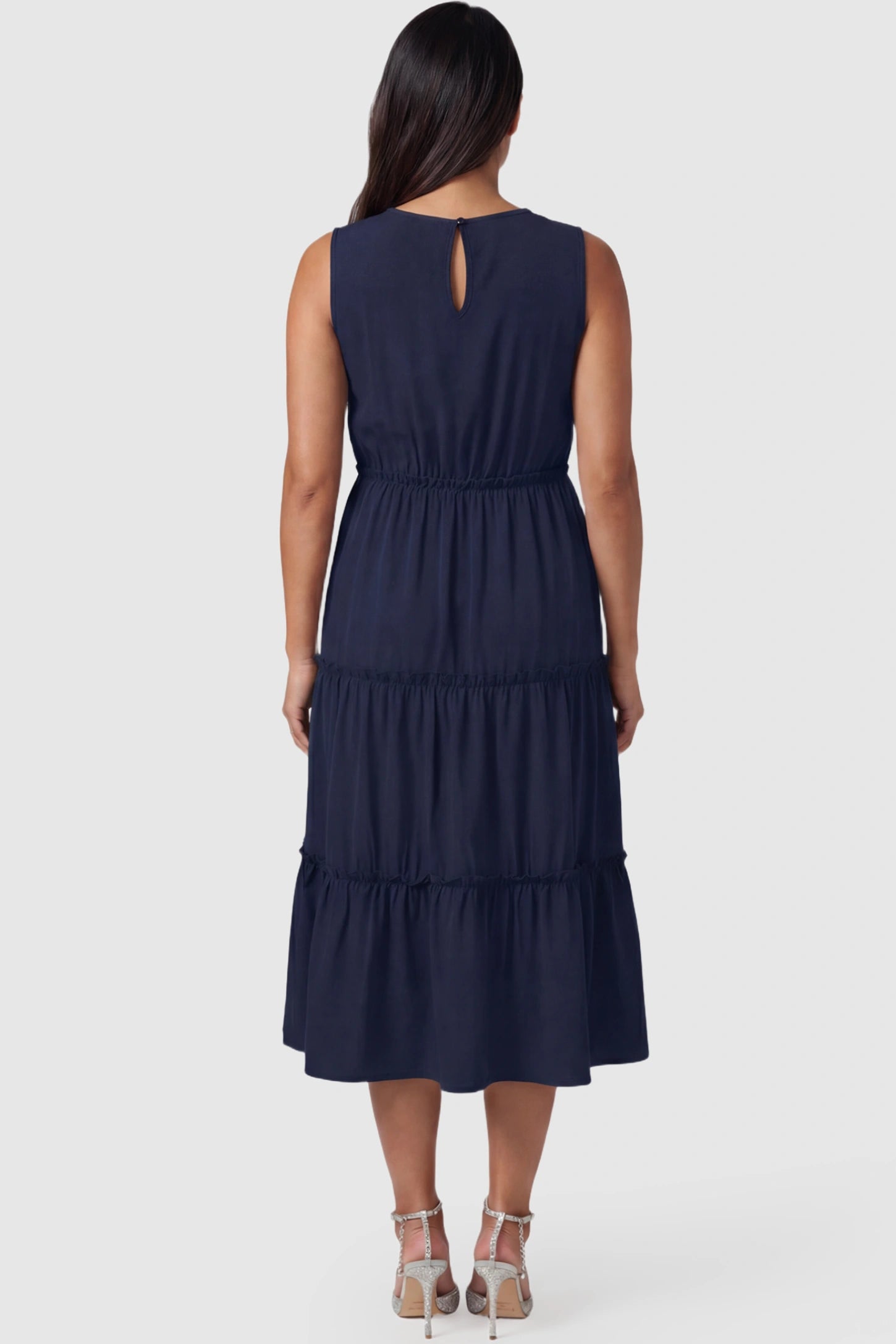 Solid Sleeveless Ruffle Tiered Maternity Midi Dress Solid Sleeveless Ruffle Tiered Maternity Midi Dress in navy blue featuring a ruffle tiered skirt on a pregnant model.