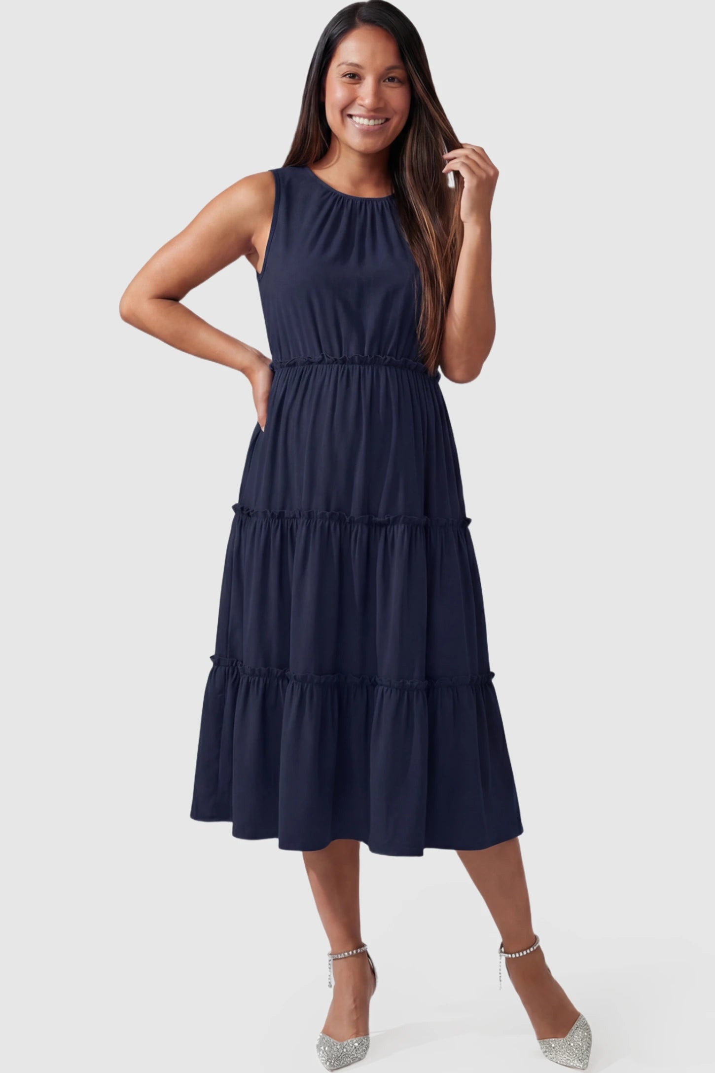 Solid Sleeveless Ruffle Tiered Maternity Midi Dress Solid Sleeveless Ruffle Tiered Maternity Midi Dress in navy blue featuring a ruffle tiered skirt on a pregnant model.