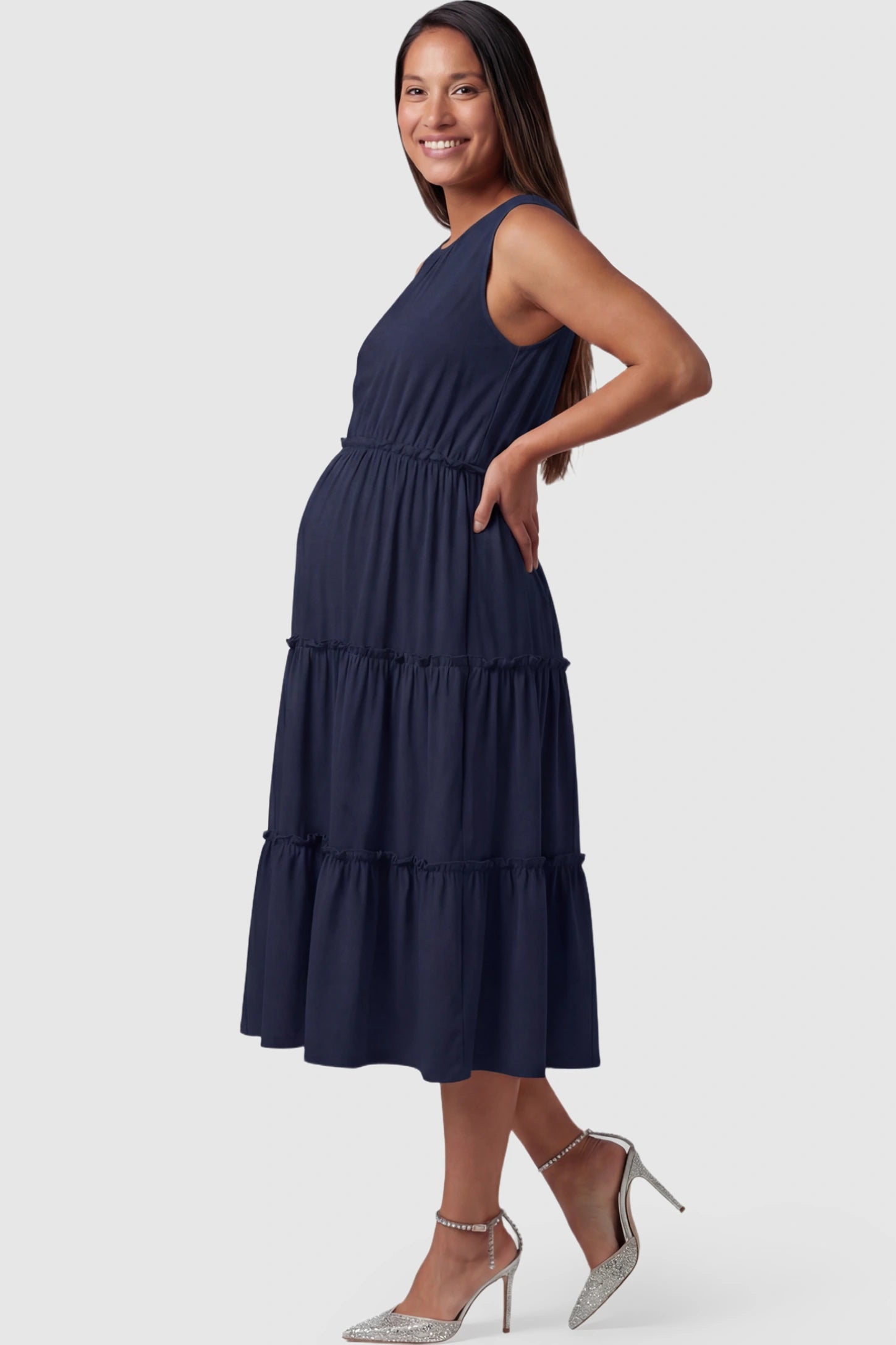 Solid Sleeveless Ruffle Tiered Maternity Midi Dress Solid Sleeveless Ruffle Tiered Maternity Midi Dress in navy blue featuring a ruffle tiered skirt on a pregnant model.