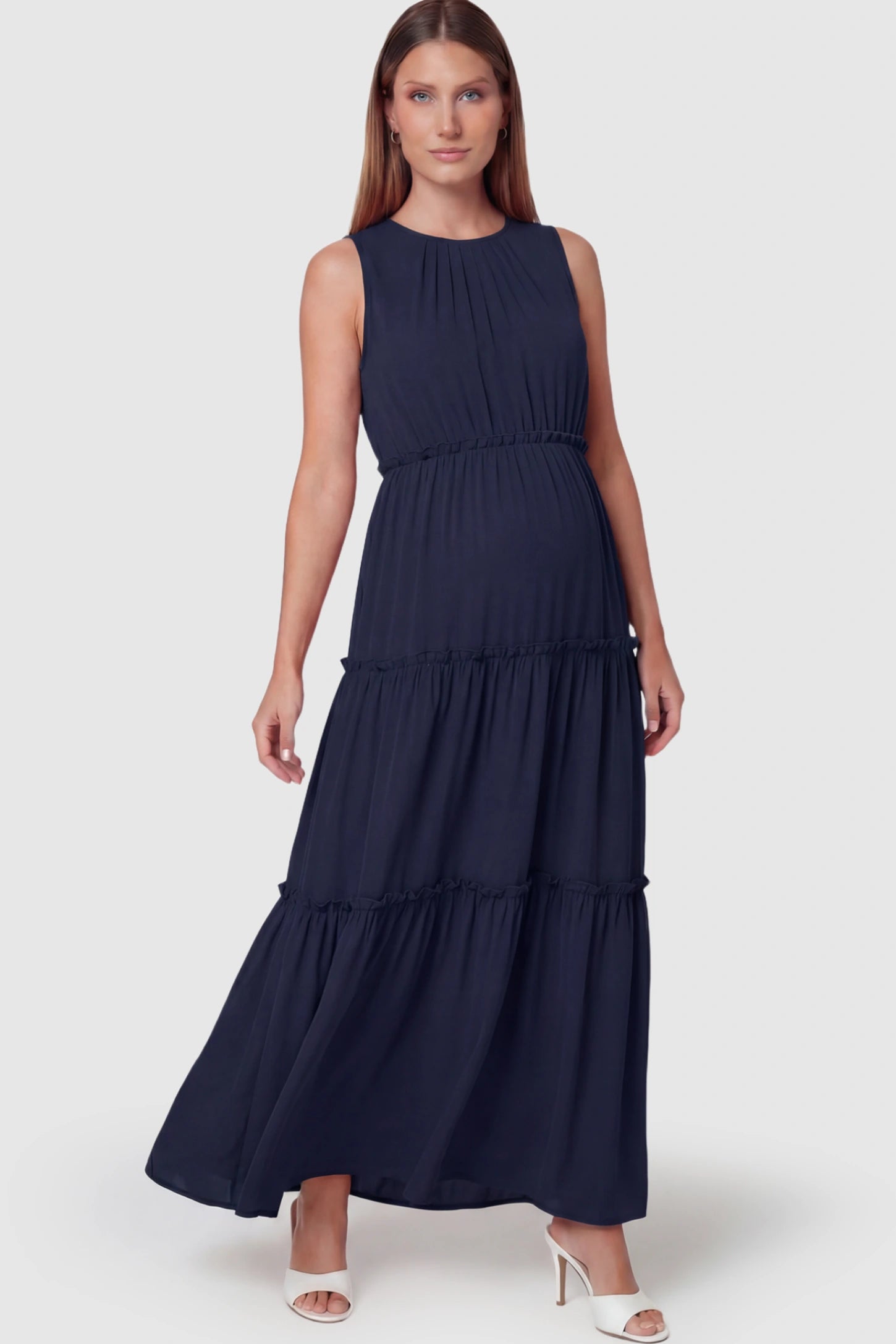 Solid Sleeveless Ruffle Tiered Maternity Midi Dress Solid Sleeveless Ruffle Tiered Maternity Midi Dress in Navy Blue featuring a ruffle tiered skirt on a pregnant model.