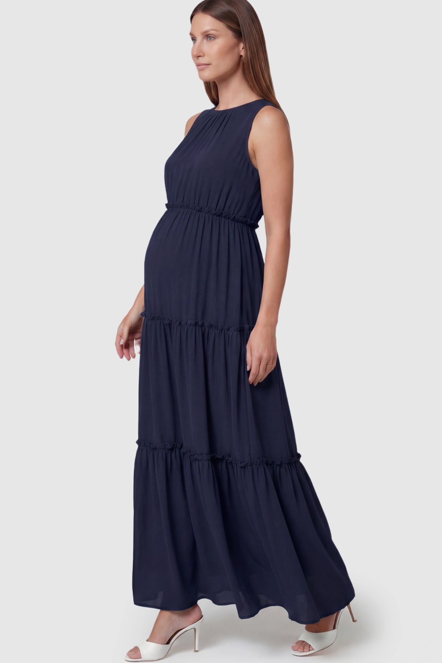 Solid Sleeveless Ruffle Tiered Maternity Midi Dress Solid Sleeveless Ruffle Tiered Maternity Midi Dress in Navy Blue featuring a ruffle tiered skirt on a pregnant model.