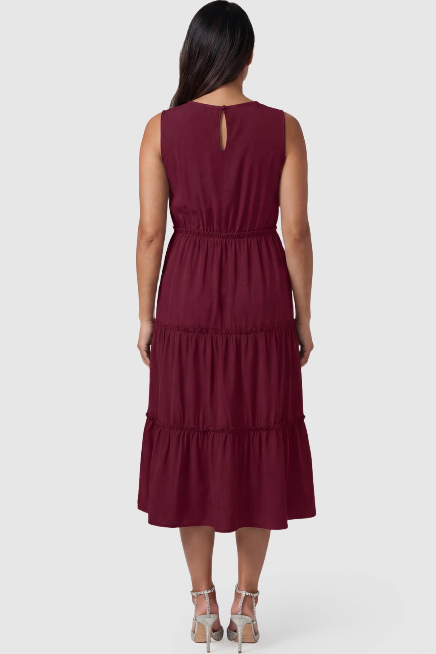 Solid Sleeveless Ruffle Tiered Maternity Midi Dress Solid Sleeveless Ruffle Tiered Maternity Midi Dress in wine red featuring a ruffle tiered skirt on a pregnant model.