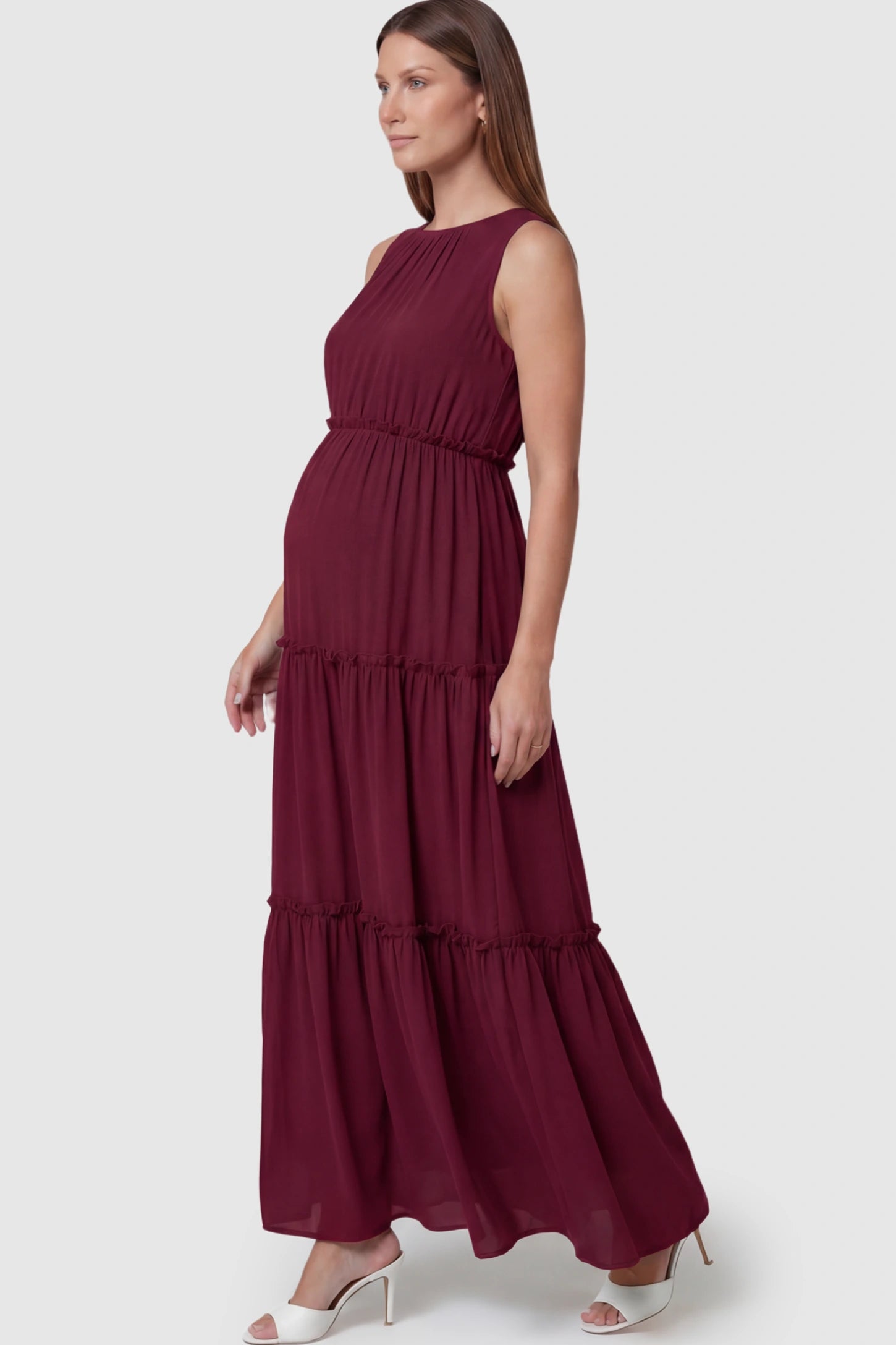 Solid Sleeveless Ruffle Tiered Maternity Midi Dress Solid Sleeveless Ruffle Tiered Maternity Midi Dress in Wine Red featuring a ruffle tiered skirt on a pregnant model.