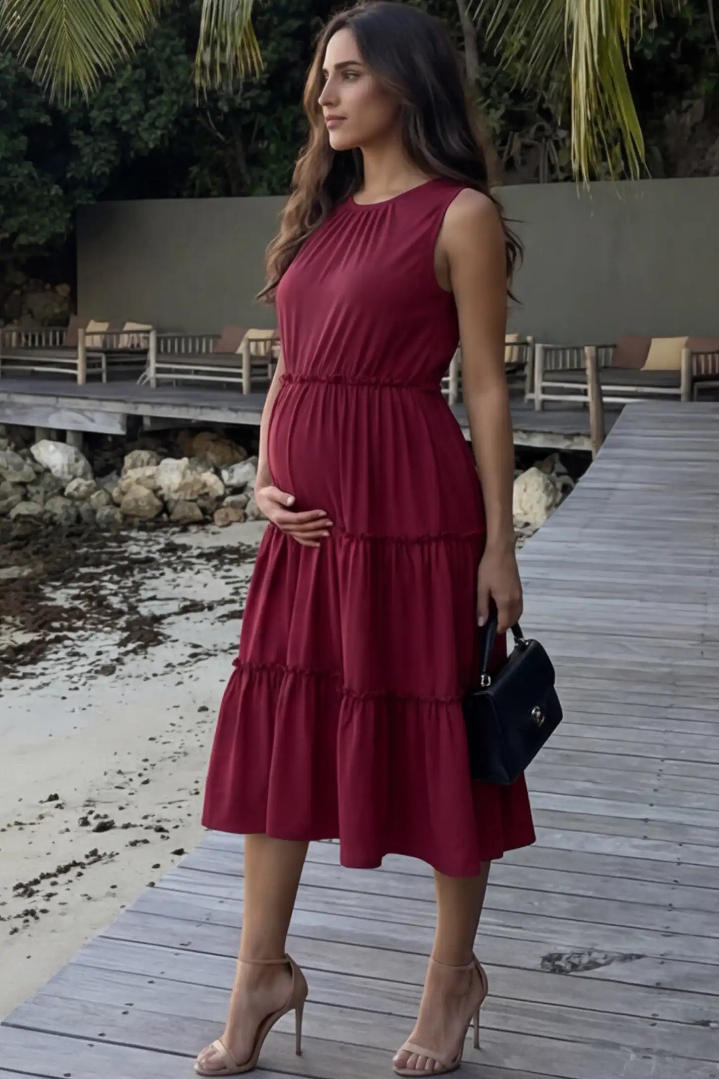 Solid Sleeveless Ruffle Tiered Maternity Midi Dress Solid Sleeveless Ruffle Tiered Maternity Midi Dress in wine red featuring a ruffle tiered skirt on a pregnant model.
