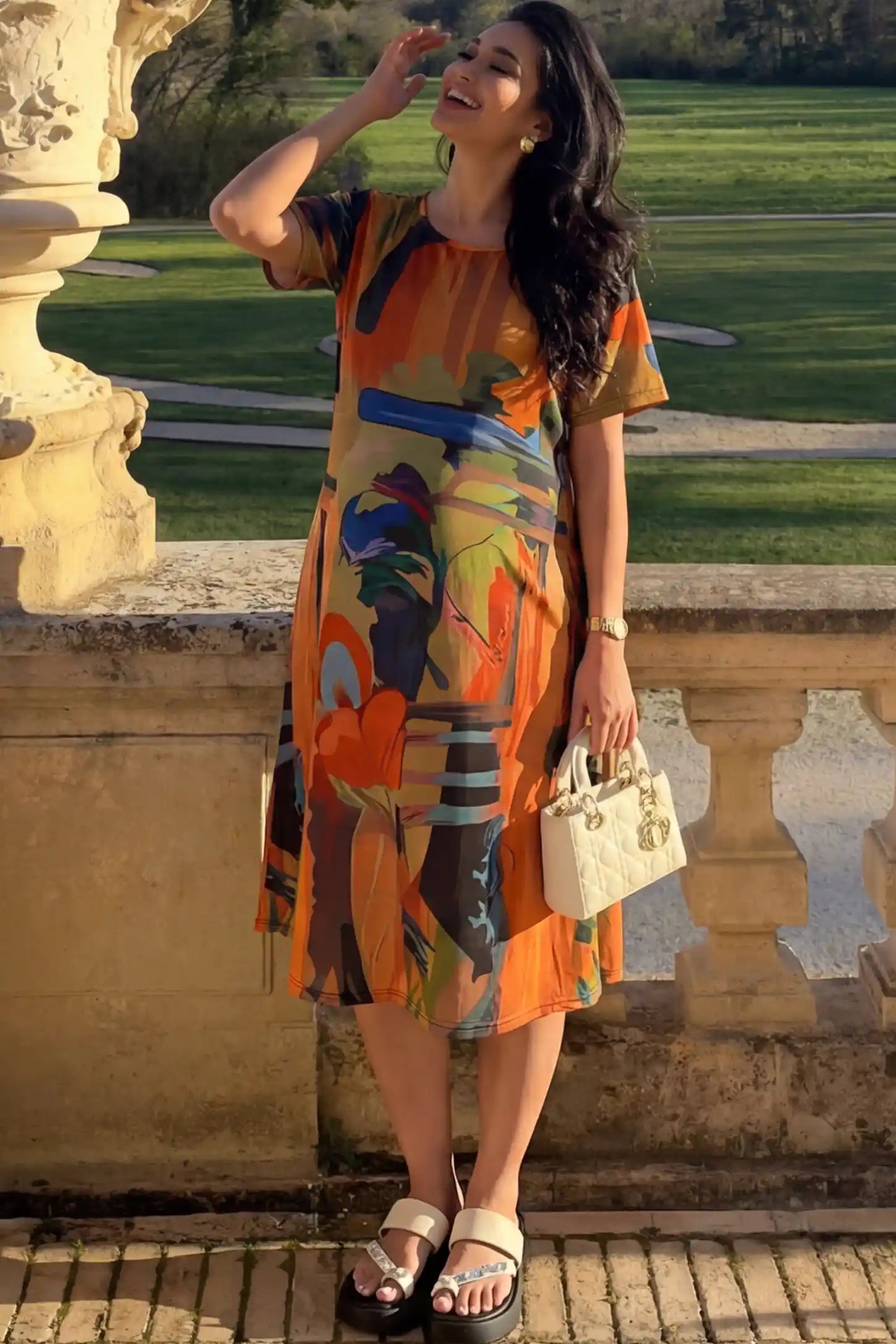 Abstract Print Scoop Neck Maternity Midi Dress in vibrant orange featuring a flowy A-line silhouette on a pregnant model.