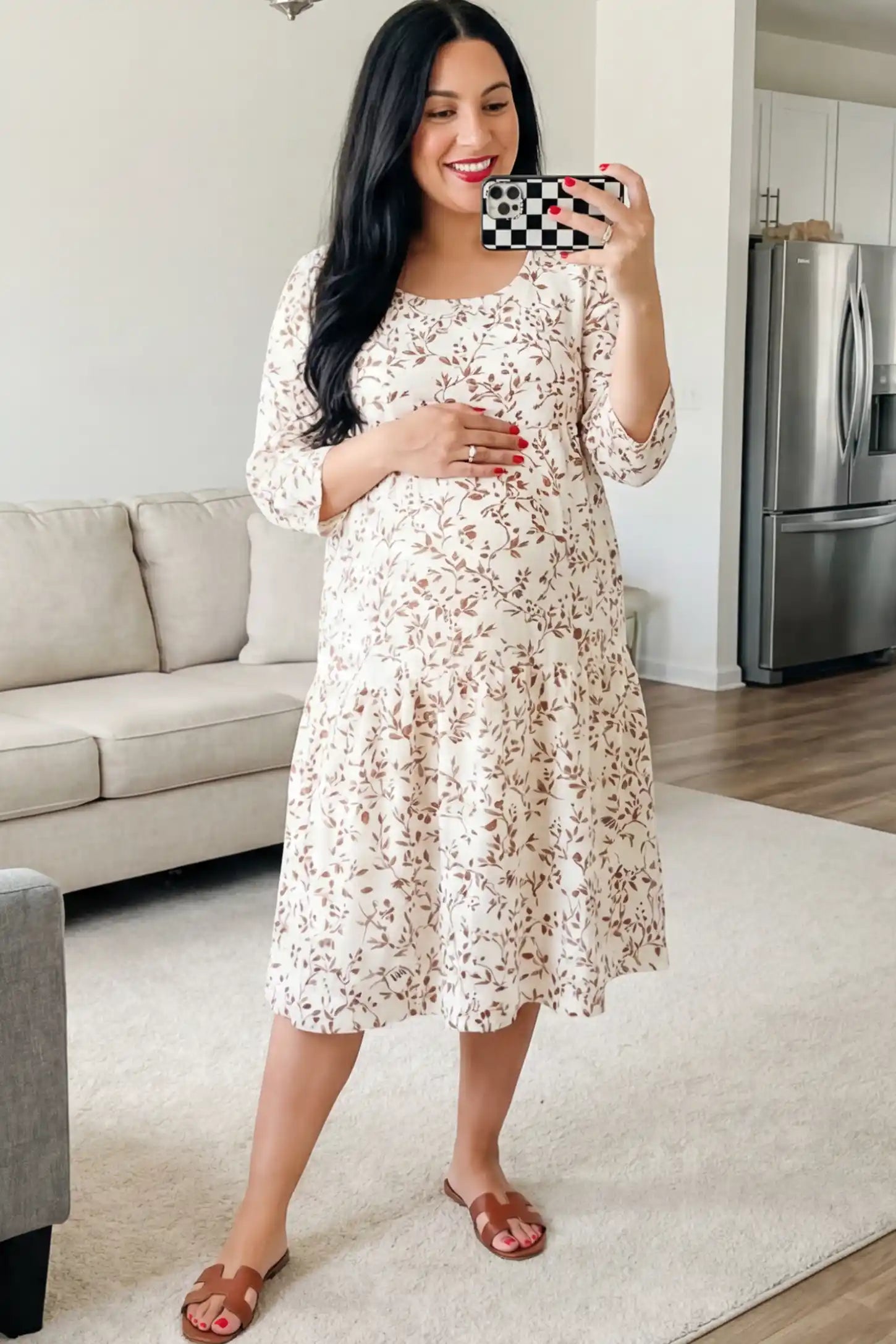 Floral Scoop Neck Tiered Maternity Midi Dress Floral Scoop Neck Tiered Midi Maternity Dress in Red featuring a sweet tiered skirt on a pregnant woman posing in a living room.