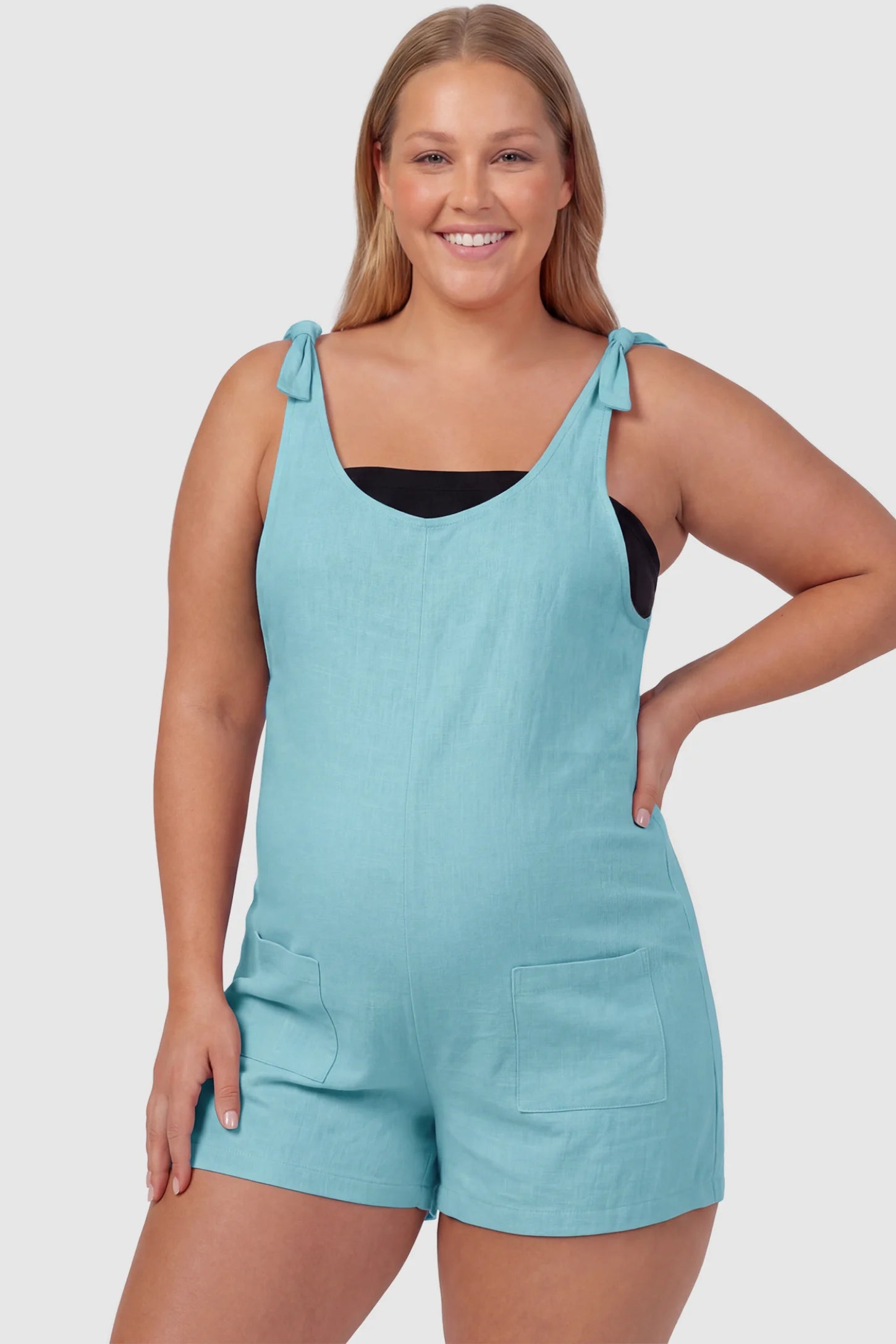 Tie-Strap Sleeveless Pocketed Maternity Romper Tie-strap sleeveless pocketed maternity romper in sky blue with adjustable tie straps and scoop neckline, front view on plus-size model