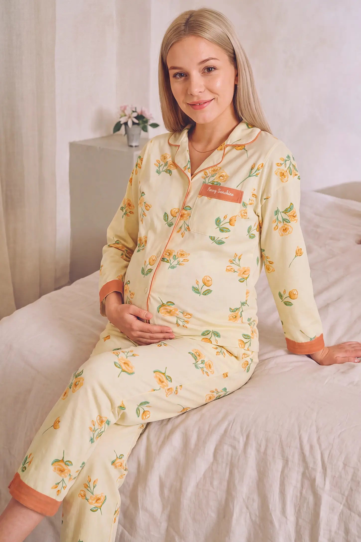 Peony Floral Organic Cotton Nursing PJ Set Peony Floral Organic Cotton Nursing PJ Set in Vintage Peony featuring gentle bump support, long sleeves with contrasting trim, and soft organic cotton fabric on a pregnant model, seated lifestyle view.