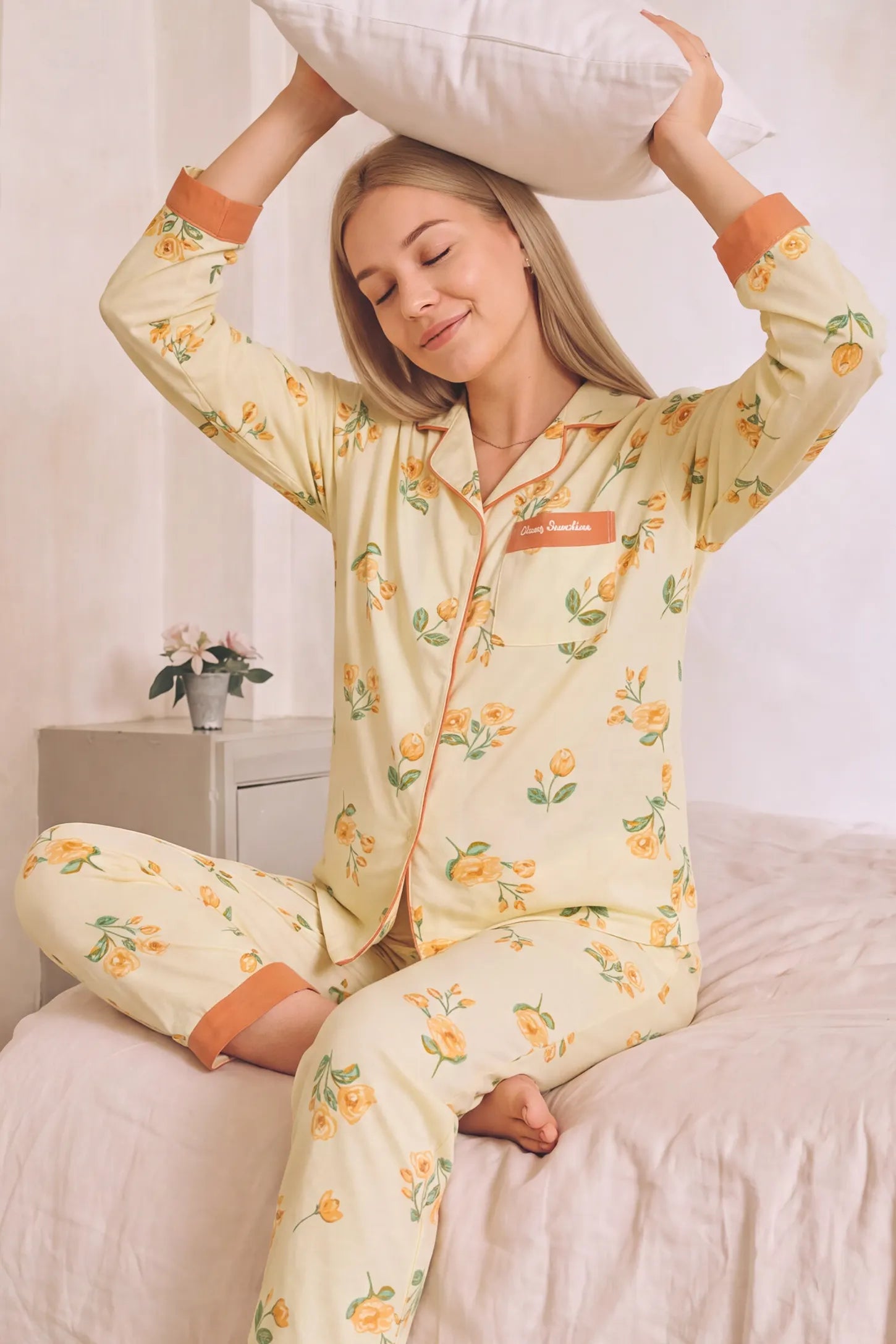 Peony Floral Organic Cotton Nursing PJ Set Peony Floral Organic Cotton Nursing PJ Set in Vintage Peony featuring comfortable relaxed fit, elastic waist with adjustable tabs, and floral pattern design on a pregnant model, playful seated bed view.