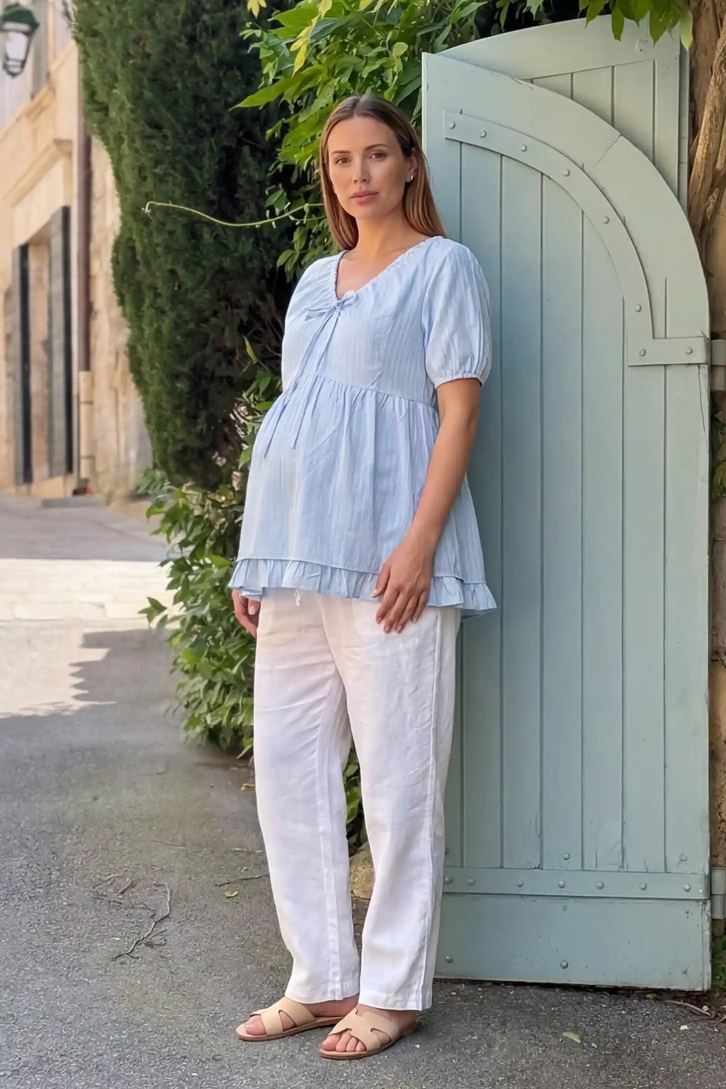 Drawstring V-Neck Peplum Maternity Top Drawstring V-neck peplum maternity top in blue with drawstring V-neck detail and puff sleeves, front view on pregnant model