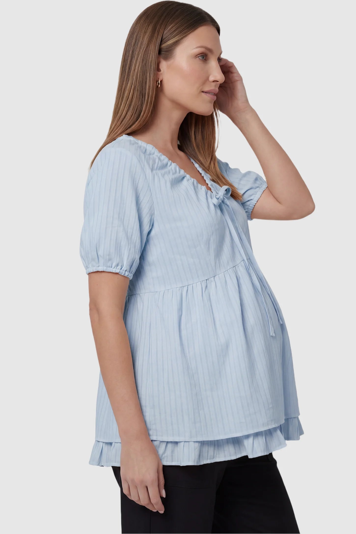 Drawstring V-neck peplum maternity top in blue with bump-friendly flowy fit, side view on pregnant model
