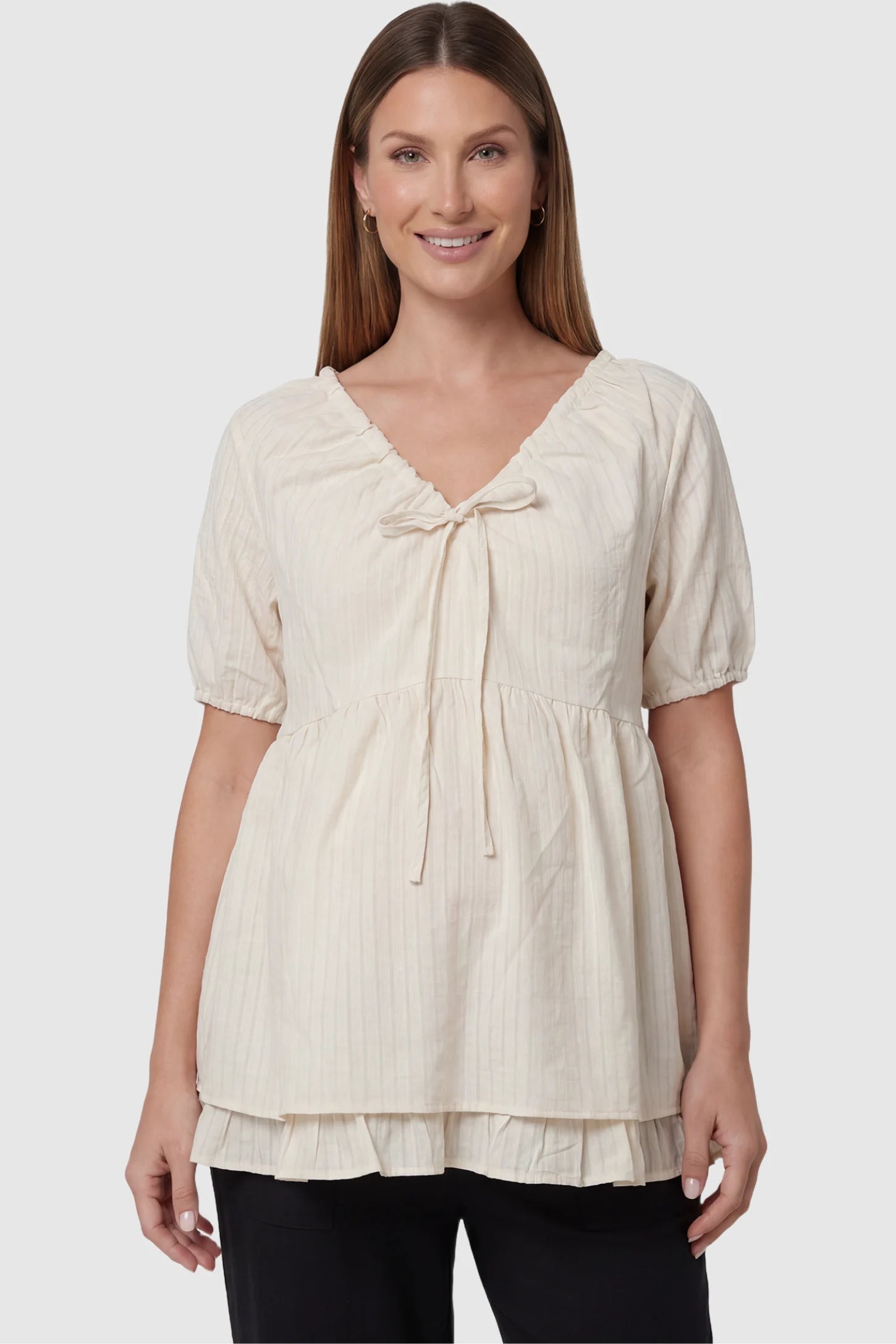 Drawstring V-Neck Peplum Maternity Top Drawstring V-neck peplum maternity top in cream with drawstring V-neck detail and puff sleeves, front view on pregnant model