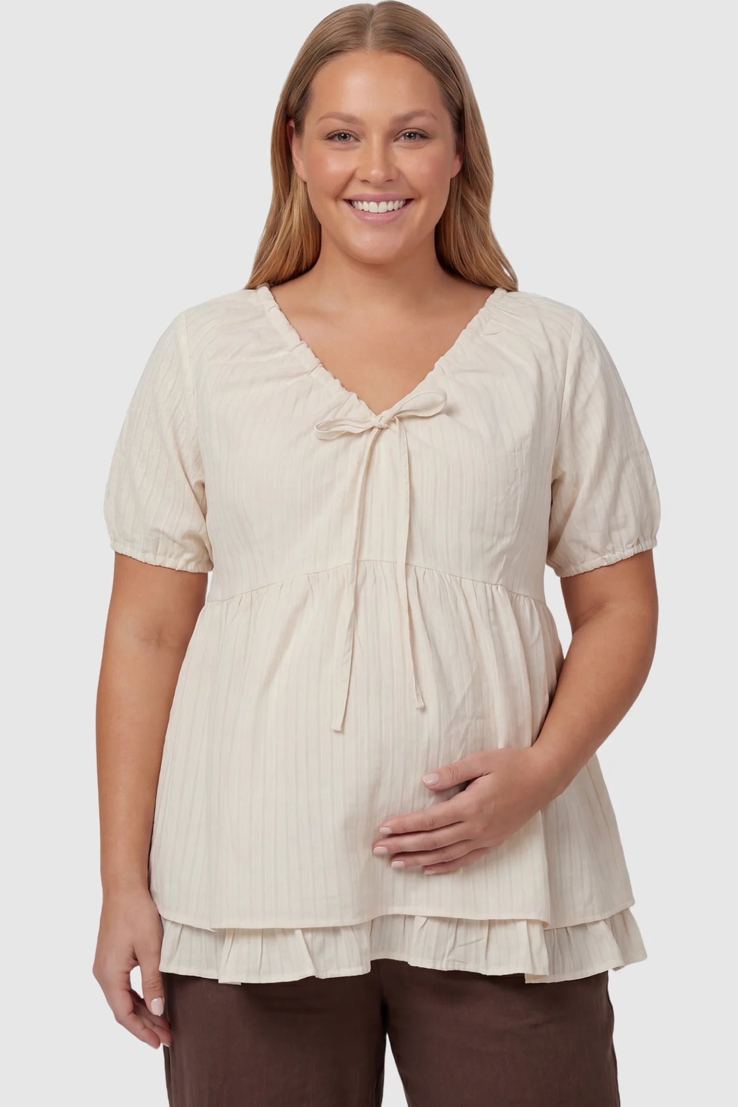 Drawstring V-Neck Peplum Maternity Top Drawstring V-neck peplum maternity top in cream with drawstring V-neck detail and puff sleeves, front view on plus-size model