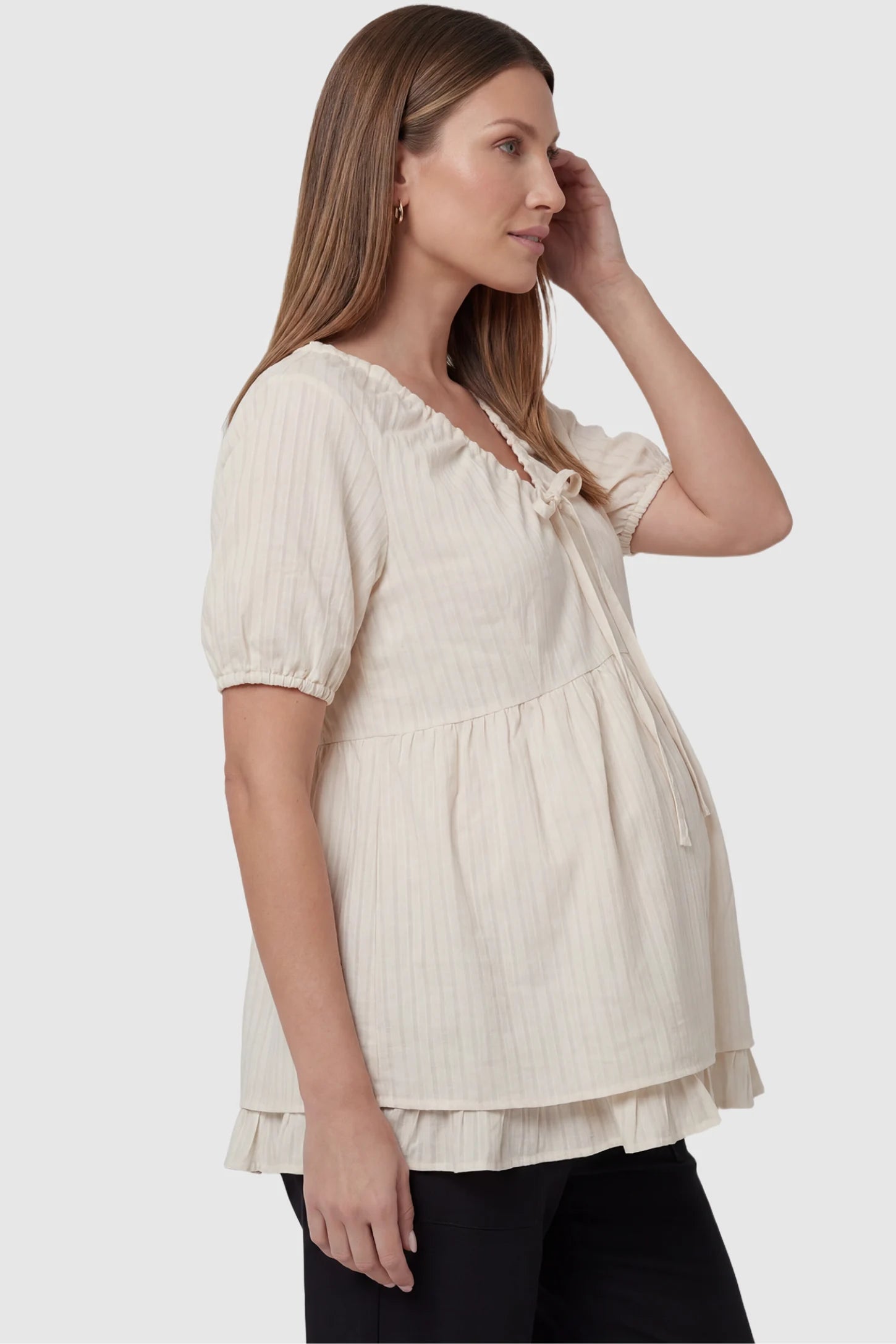 Drawstring V-Neck Peplum Maternity Top Drawstring V-neck peplum maternity top in cream with bump-friendly flowy fit, side view on pregnant model