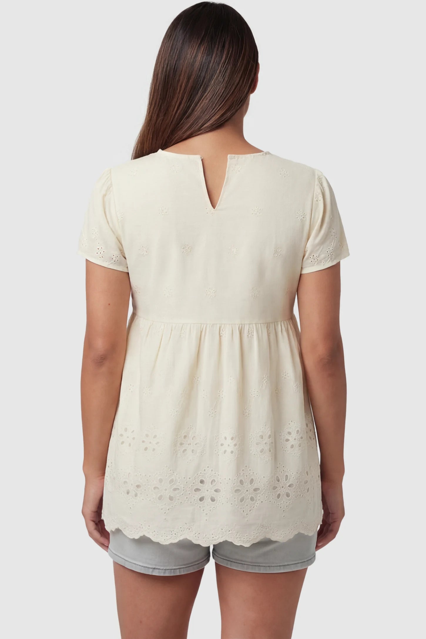 Floral Eyelet Round Neck Peplum Maternity Top Floral eyelet round neck peplum maternity top in pale yellow with delicate floral eyelet detail, back view on pregnant model