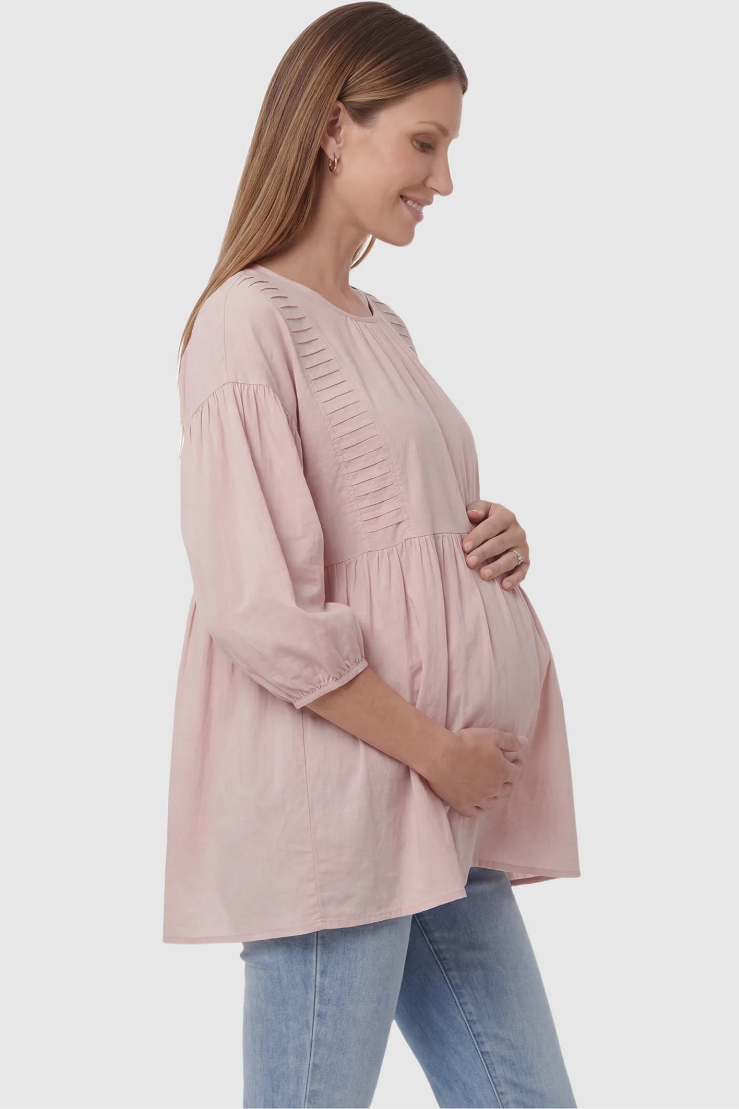 Peplum round neck maternity blouse in pink with flowy peplum and 3/4 sleeves, side view on pregnant model